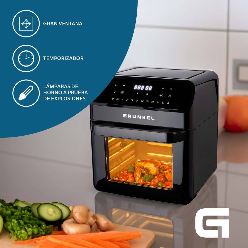 Un forno nero che cucina pollo e verdure, con verdure fresche nelle vicinanze.