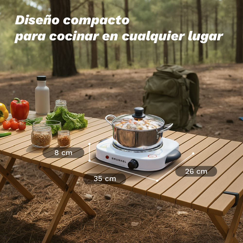 Un hornillo eléctrico portátil con olla sobre mesa de madera en bosque. Verduras y frascos cerca.