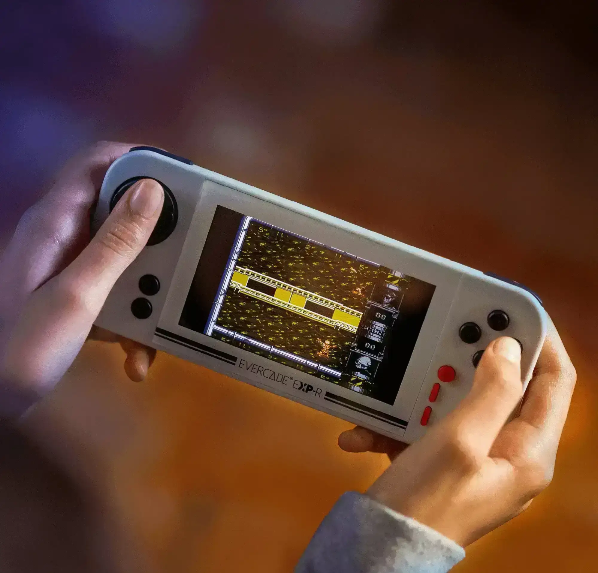 Mani tengono un dispositivo da gioco portatile con un gioco retrò sullo schermo.