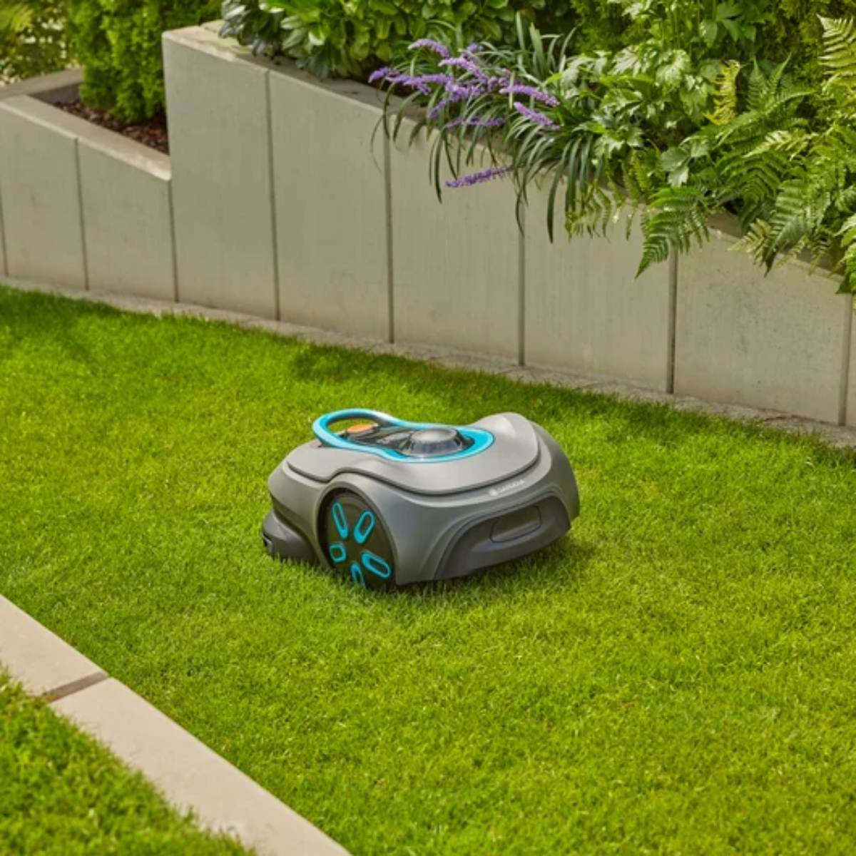 Un robot cortacésped gris con detalles azules está sobre un césped verde.