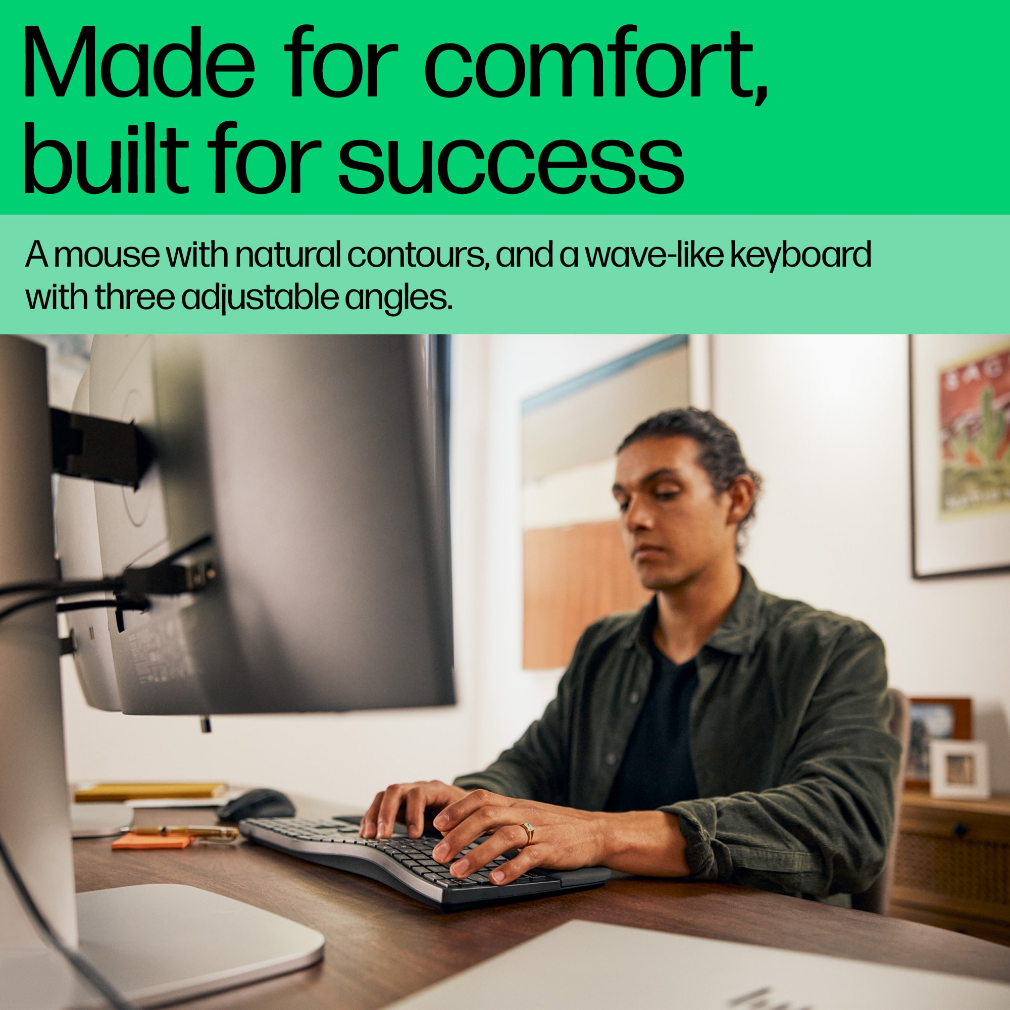 Man types on a wave-like keyboard, a monitor is in front of him.