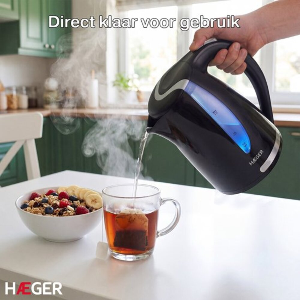 Une main verse de l'eau chaude d'une bouilloire noire dans une tasse de thé à côté d'un bol de céréales.