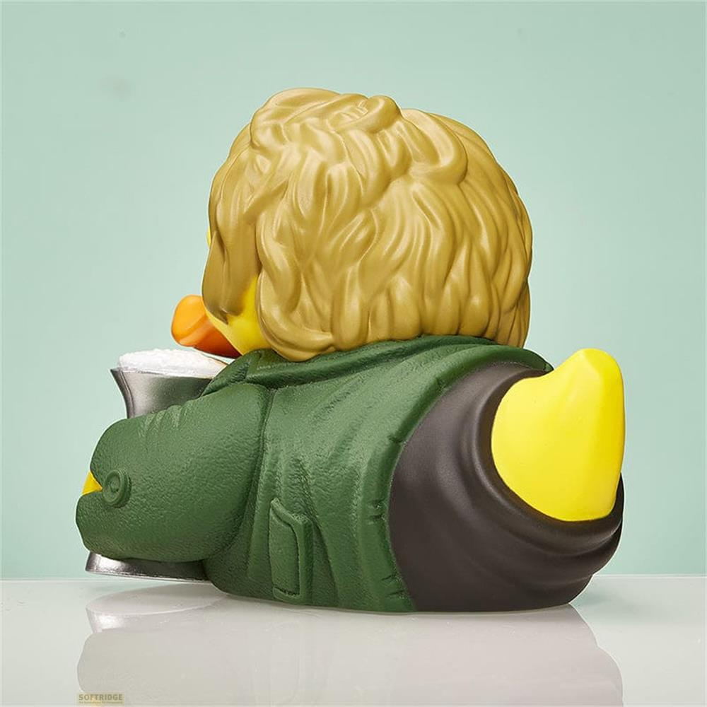 Eine gelbe Gummiente mit blonden Haaren und einem grünen Mantel trinkt aus einem Becher.