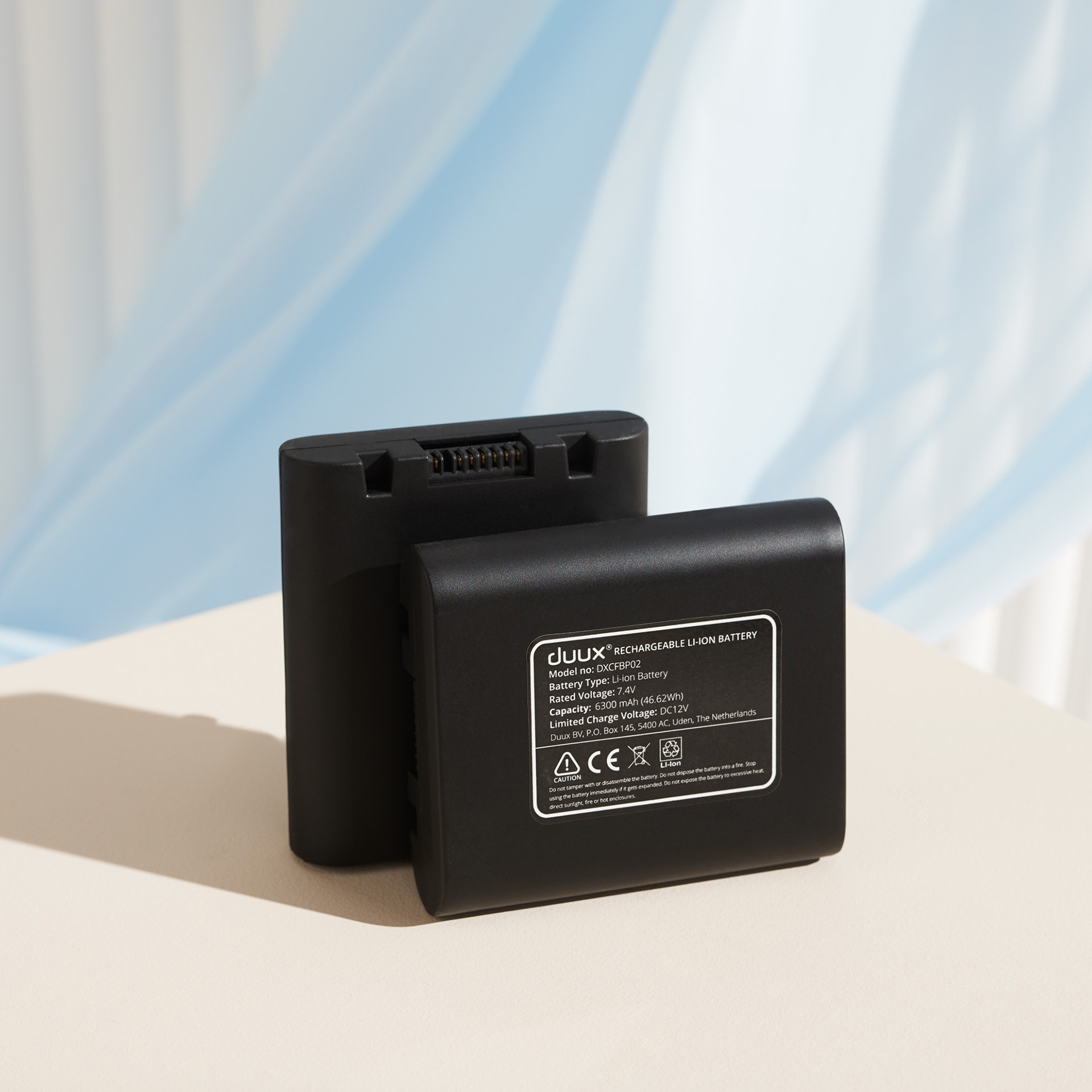 Twee zwarte batterijen naast elkaar op een lichte ondergrond. Eén voor, één achter.