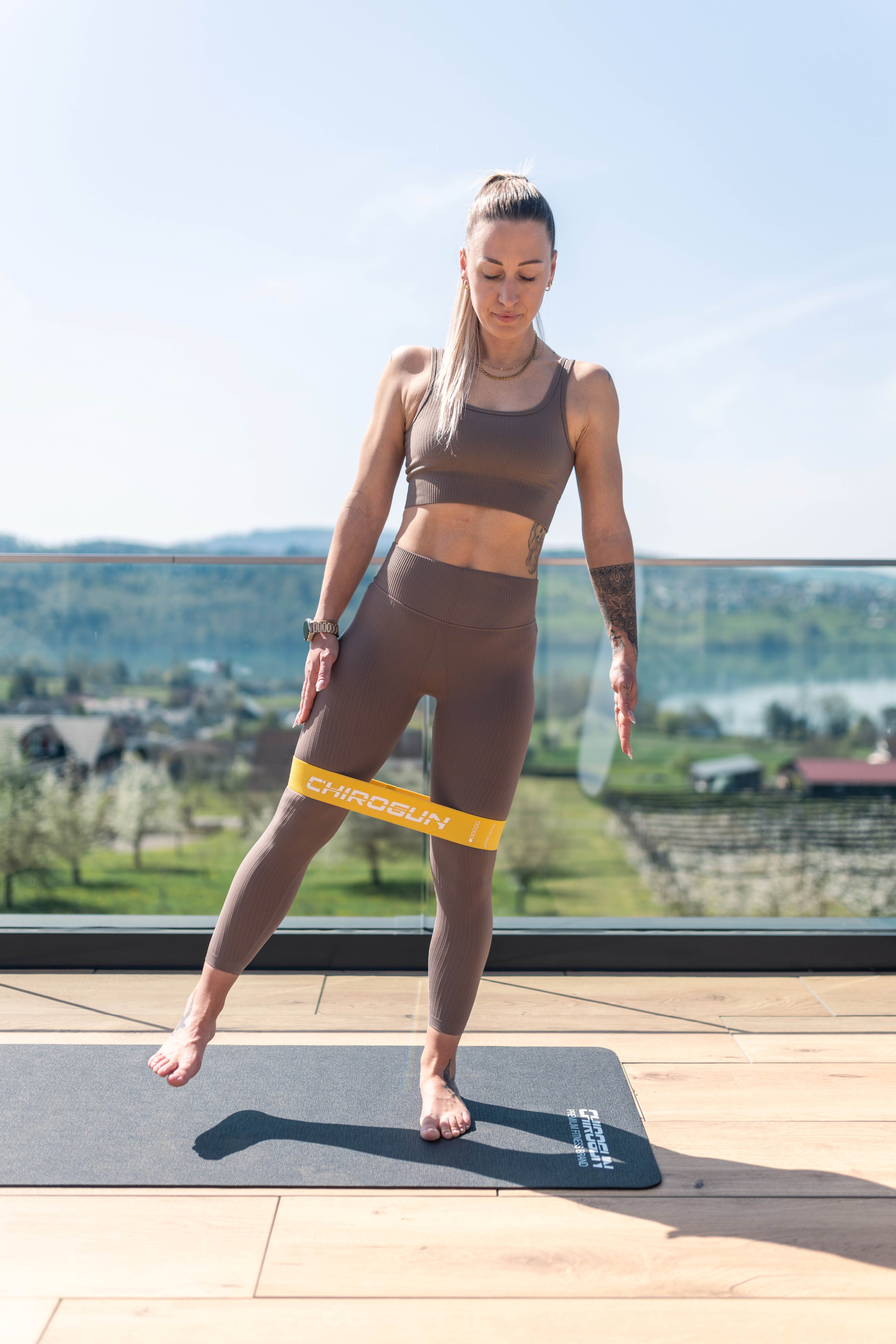Frau macht Beinübungen mit Widerstandsband auf einer Matte im Freien.