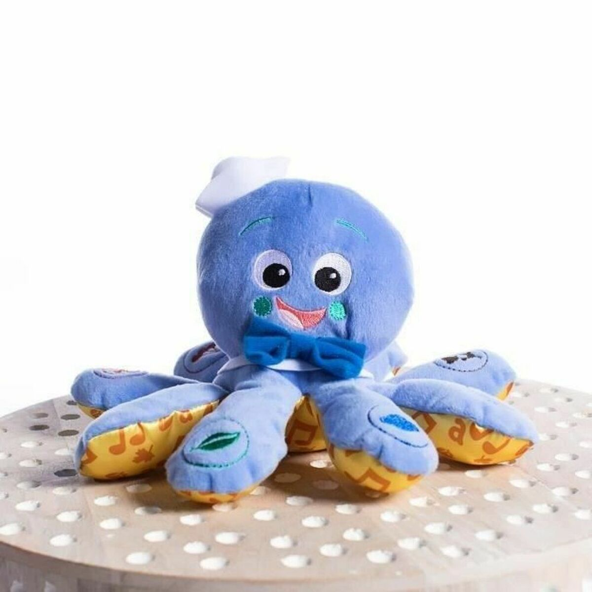 Ein blauer Plüsch-Oktopus mit Schleife und Hut sitzt auf einem Tisch.