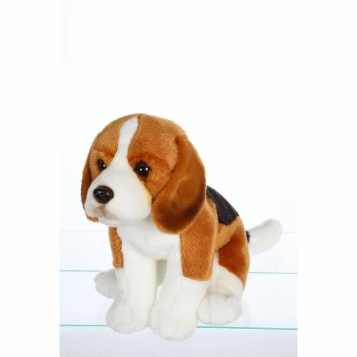 Un peluche de beagle marrón y blanco sentado sobre una superficie de cristal.