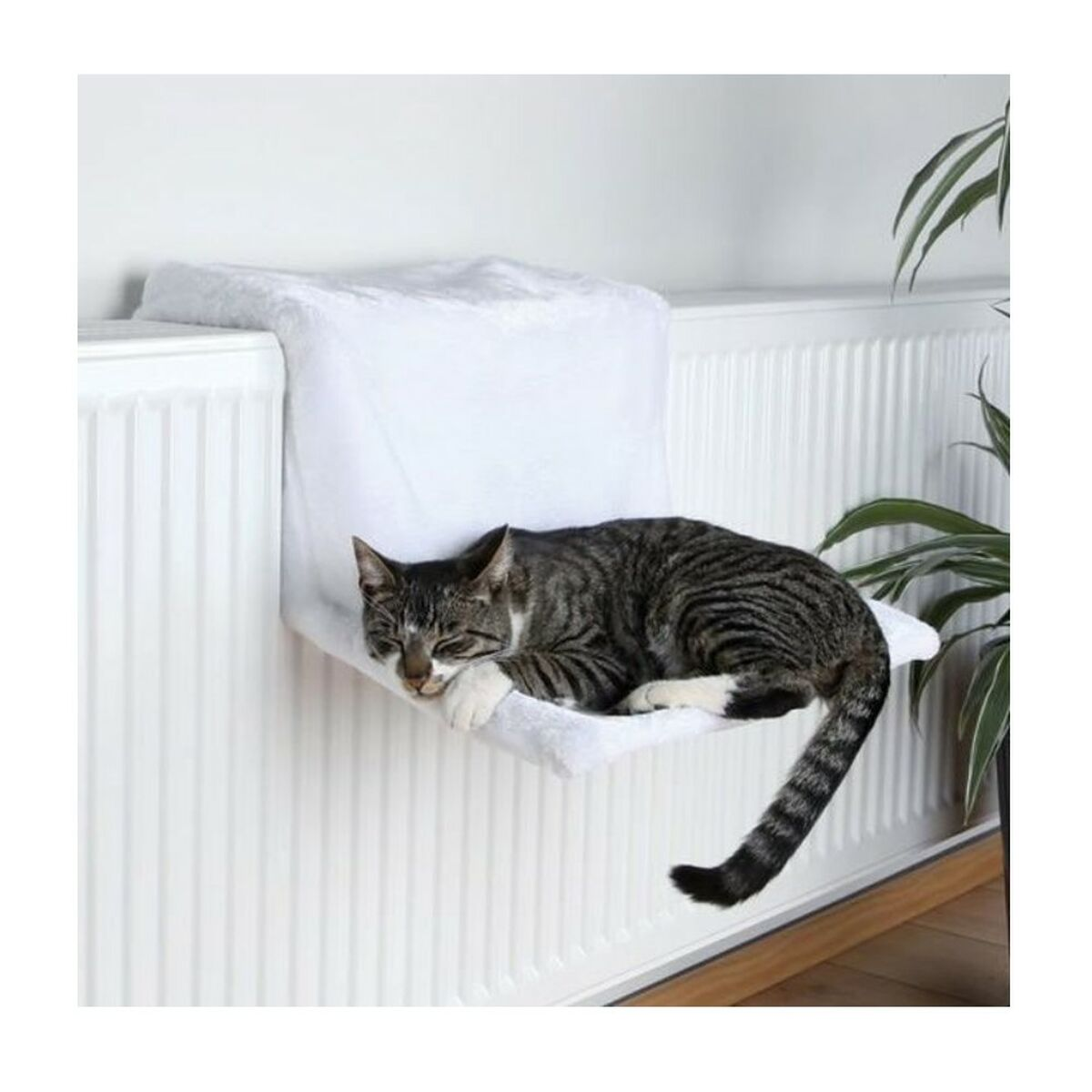 Un gato atigrado duerme en una cama blanca para radiador.