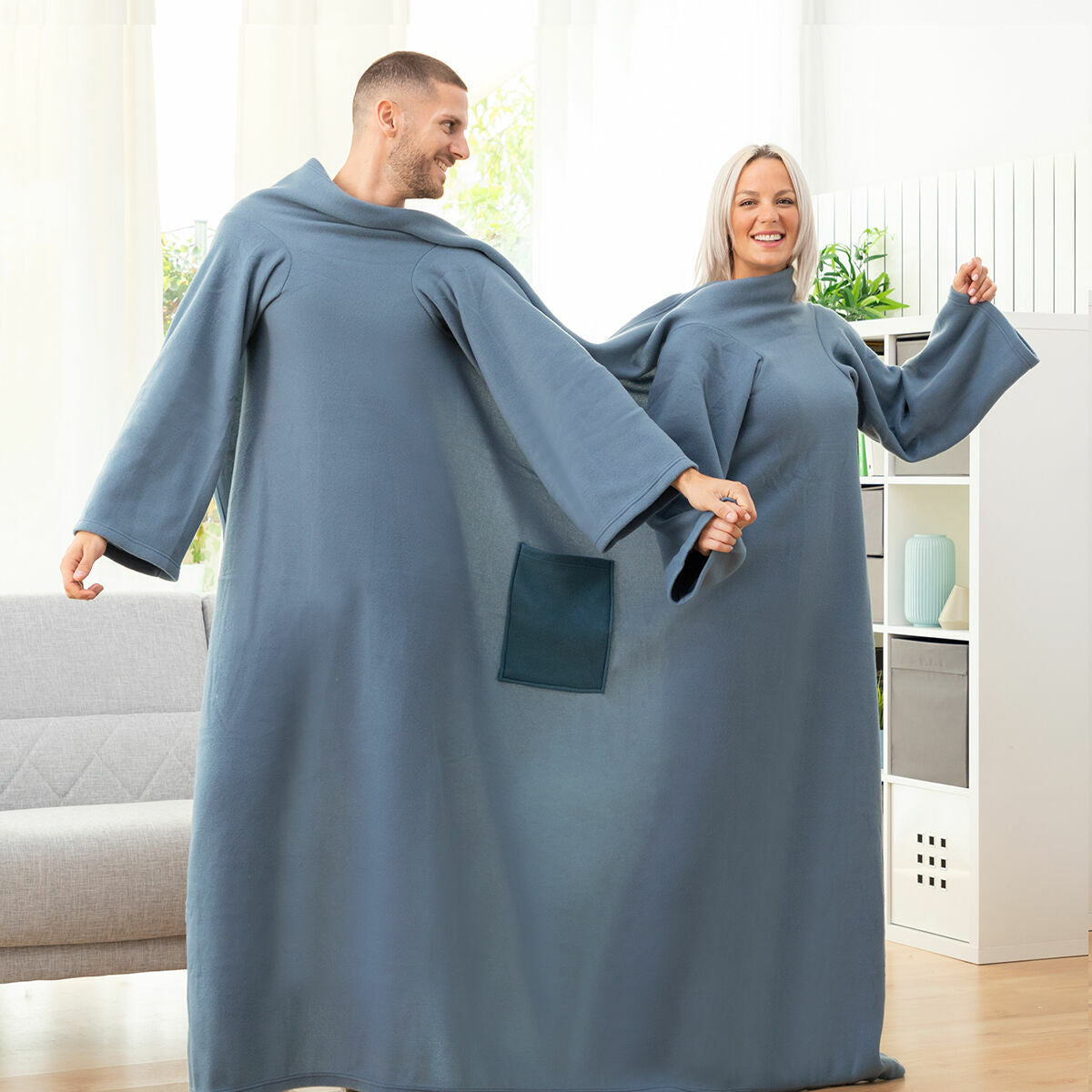 Ein Mann und eine Frau in blauen Decken mit Ärmeln halten Händchen.