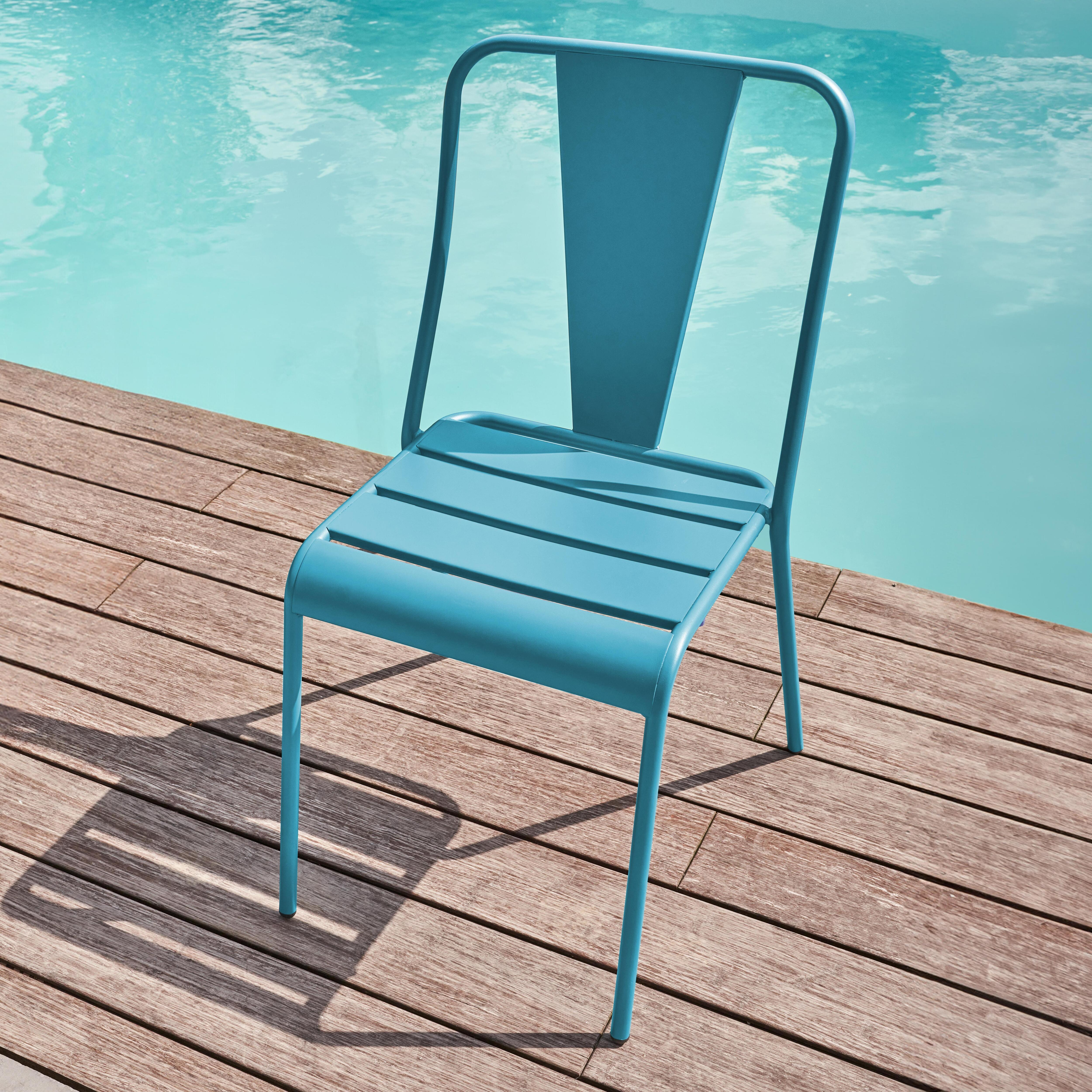 Eine blaue Metallliege steht auf einem Holzdeck neben einem Pool.