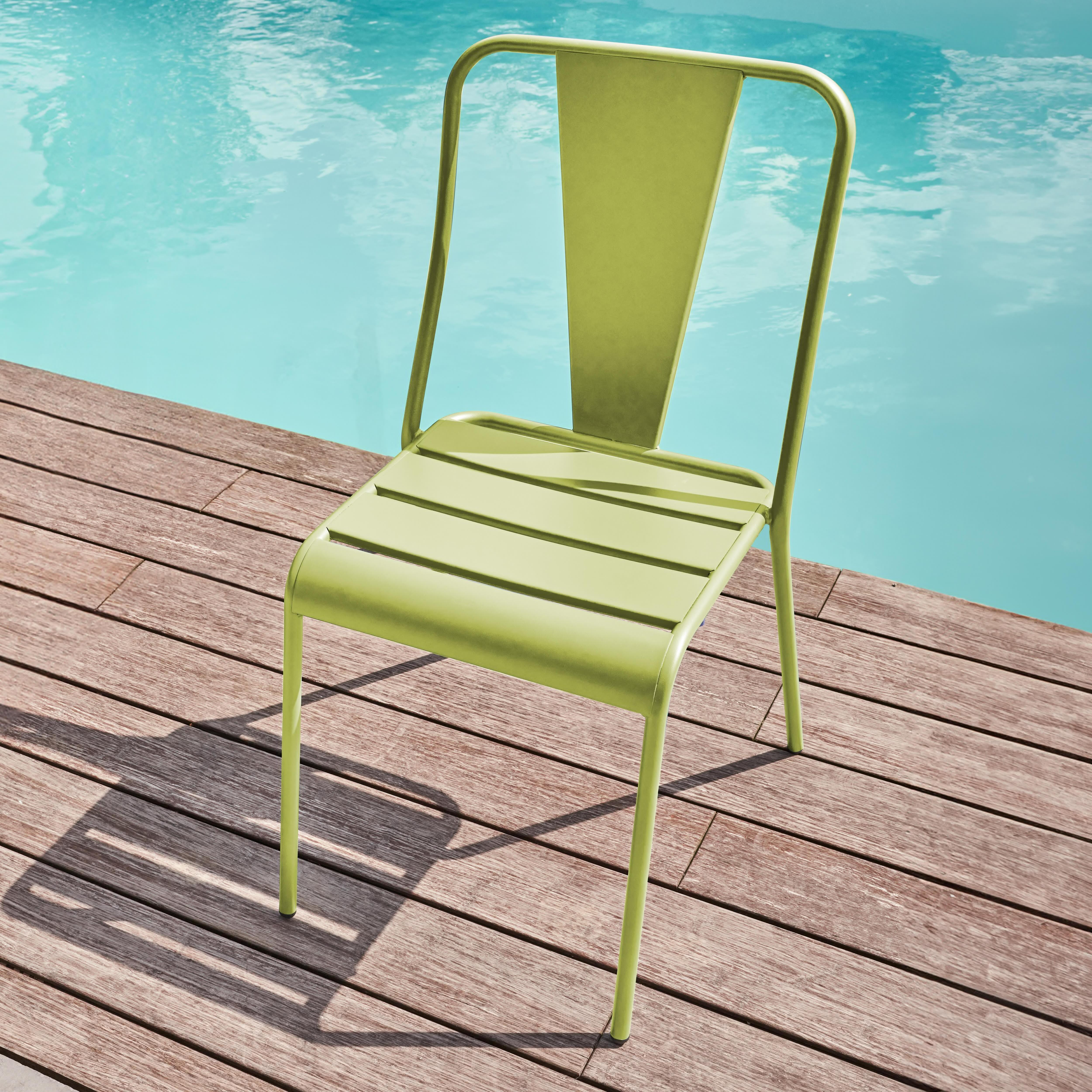 Ein leuchtend grüner Metallstuhl steht auf einer Holzterrasse neben einem Pool.