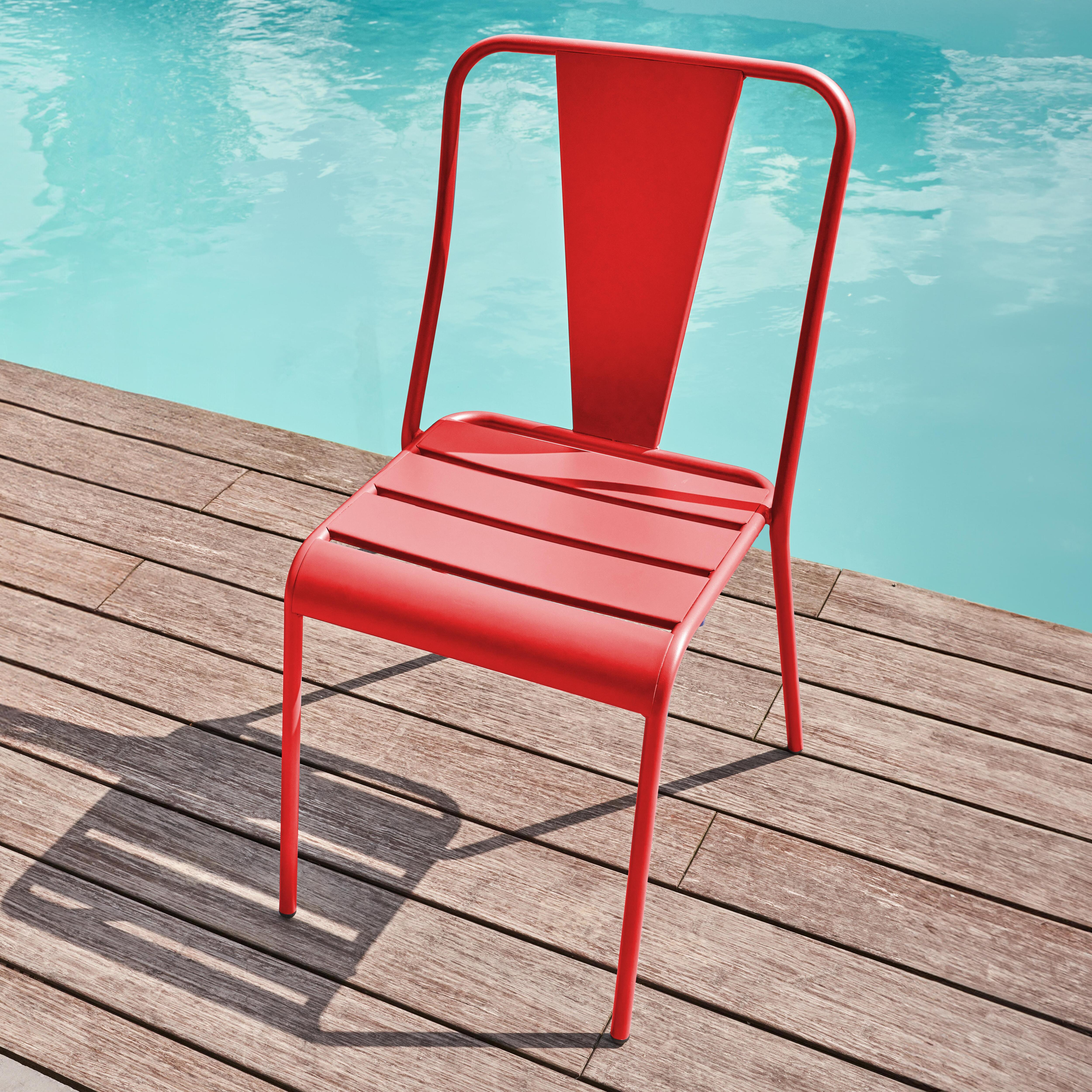 Ein roter Metallstuhl steht auf einer Holzterrasse neben einem Pool.