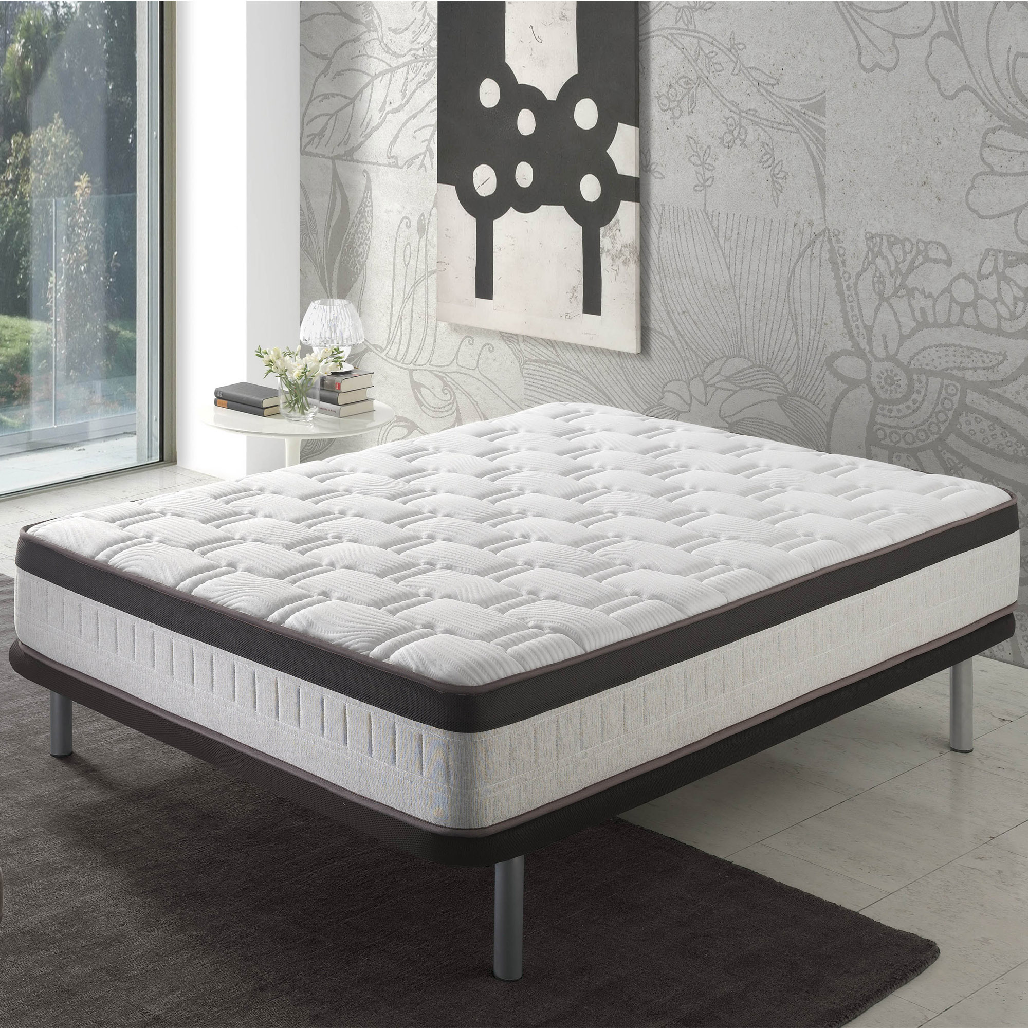 Una cama de colchón blanca con borde oscuro sobre una alfombra oscura.