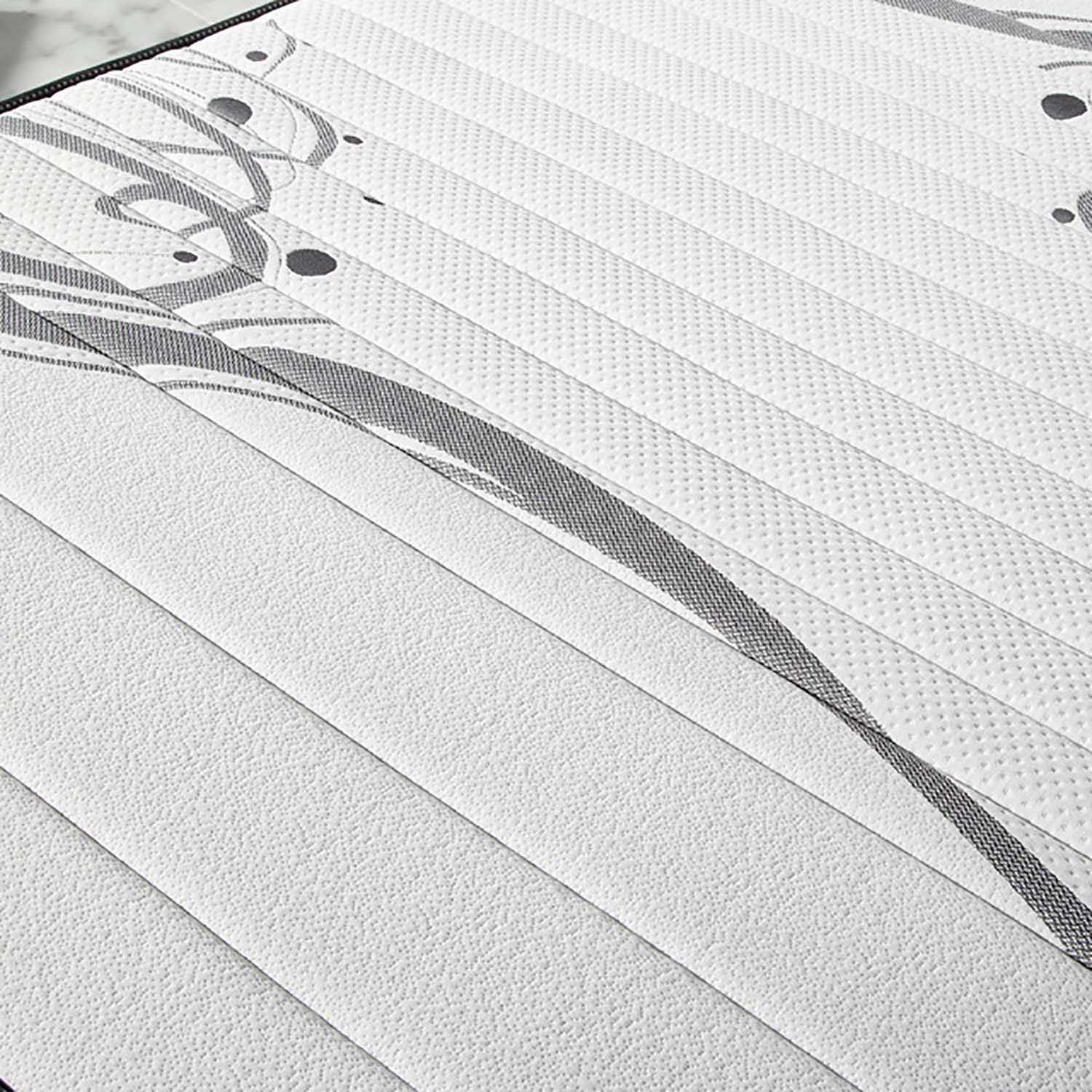 Primer plano de un colchón blanco con patrones grises arremolinados y líneas acolchadas.