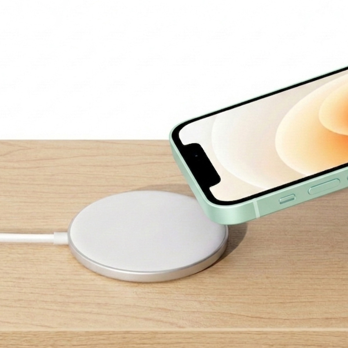 A mint green smartphone is placed over a white charging pad.