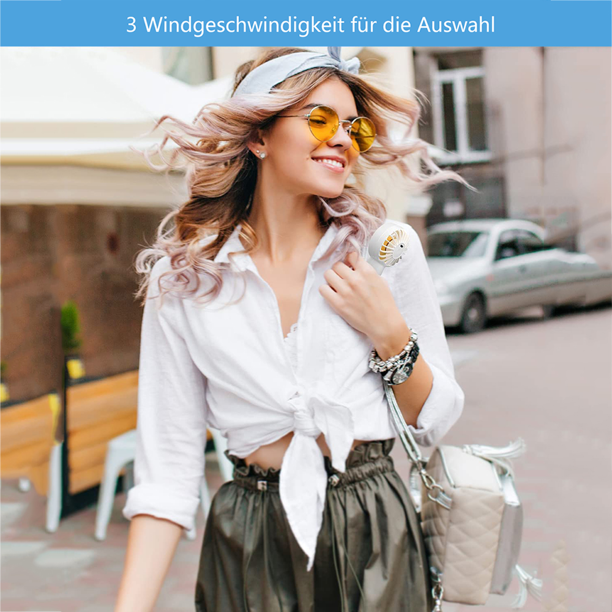 Frau mit Fächer und Sonnenbrille im Freien, Haare wehen.