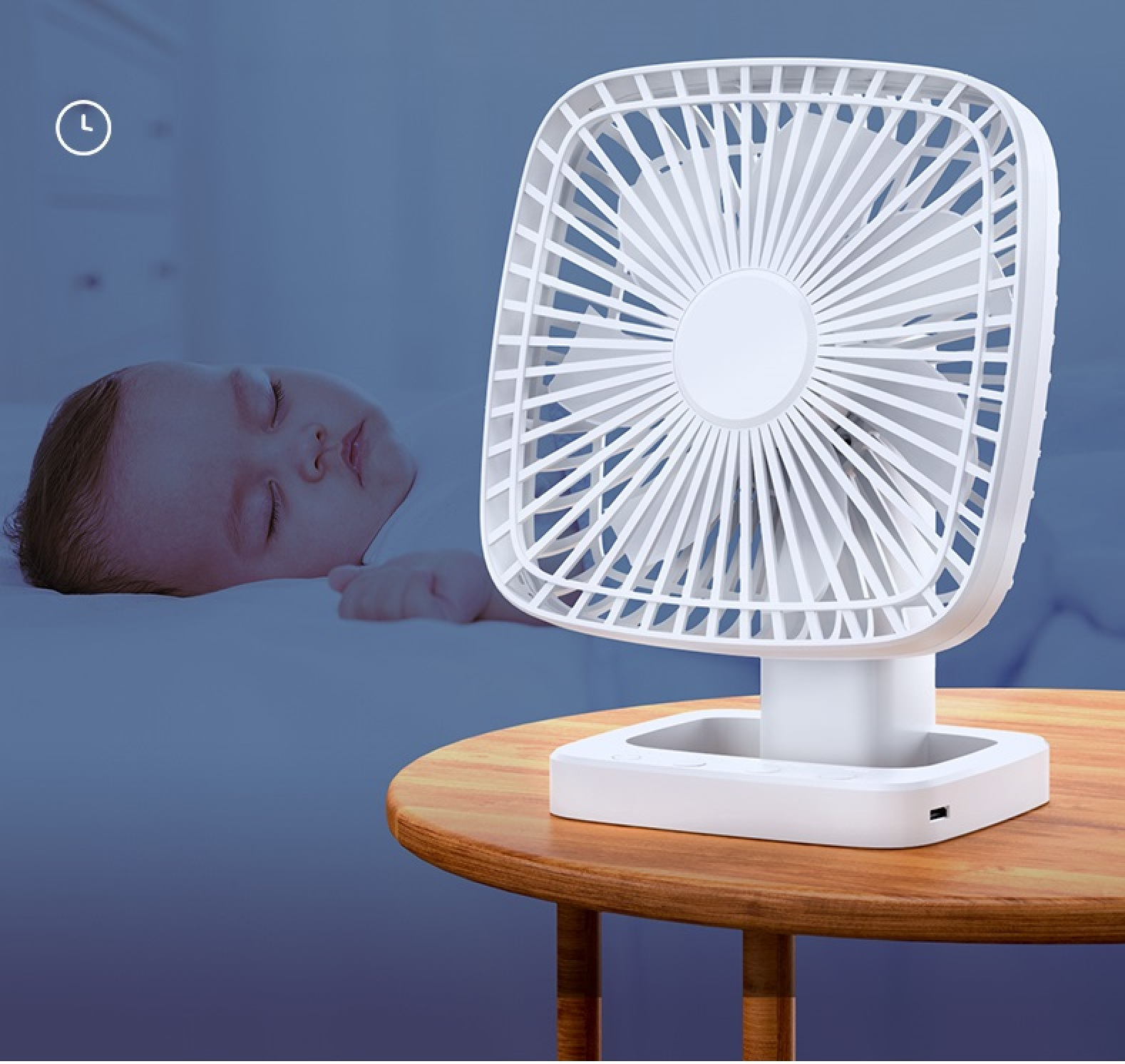 Ein weißer Ventilator steht auf einem Holztisch neben einem schlafenden Baby.