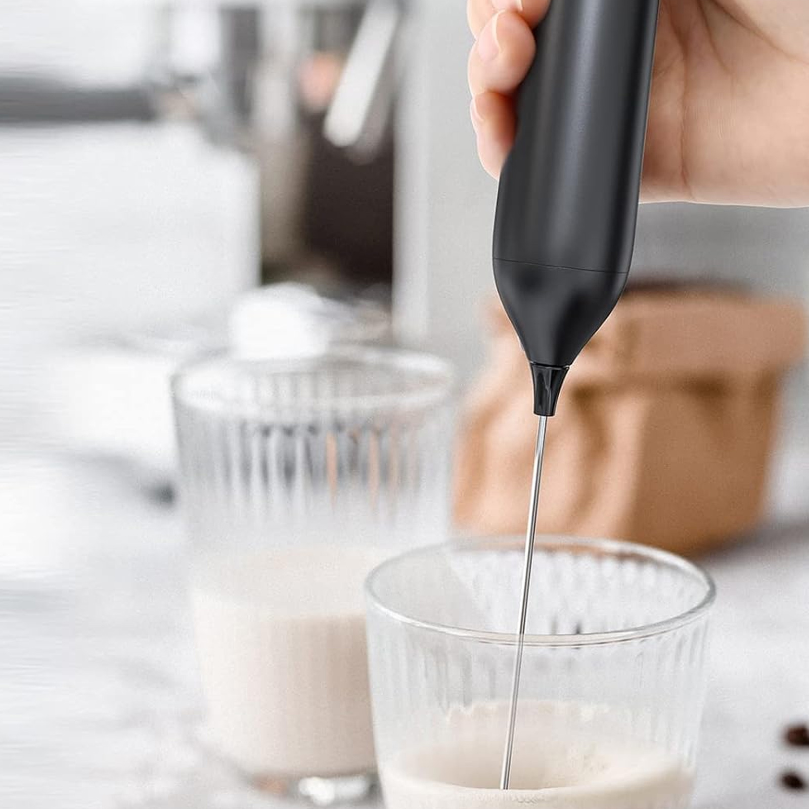 Ein schwarzer Milchaufschäumer wird in einem Glas mit Milch verwendet.