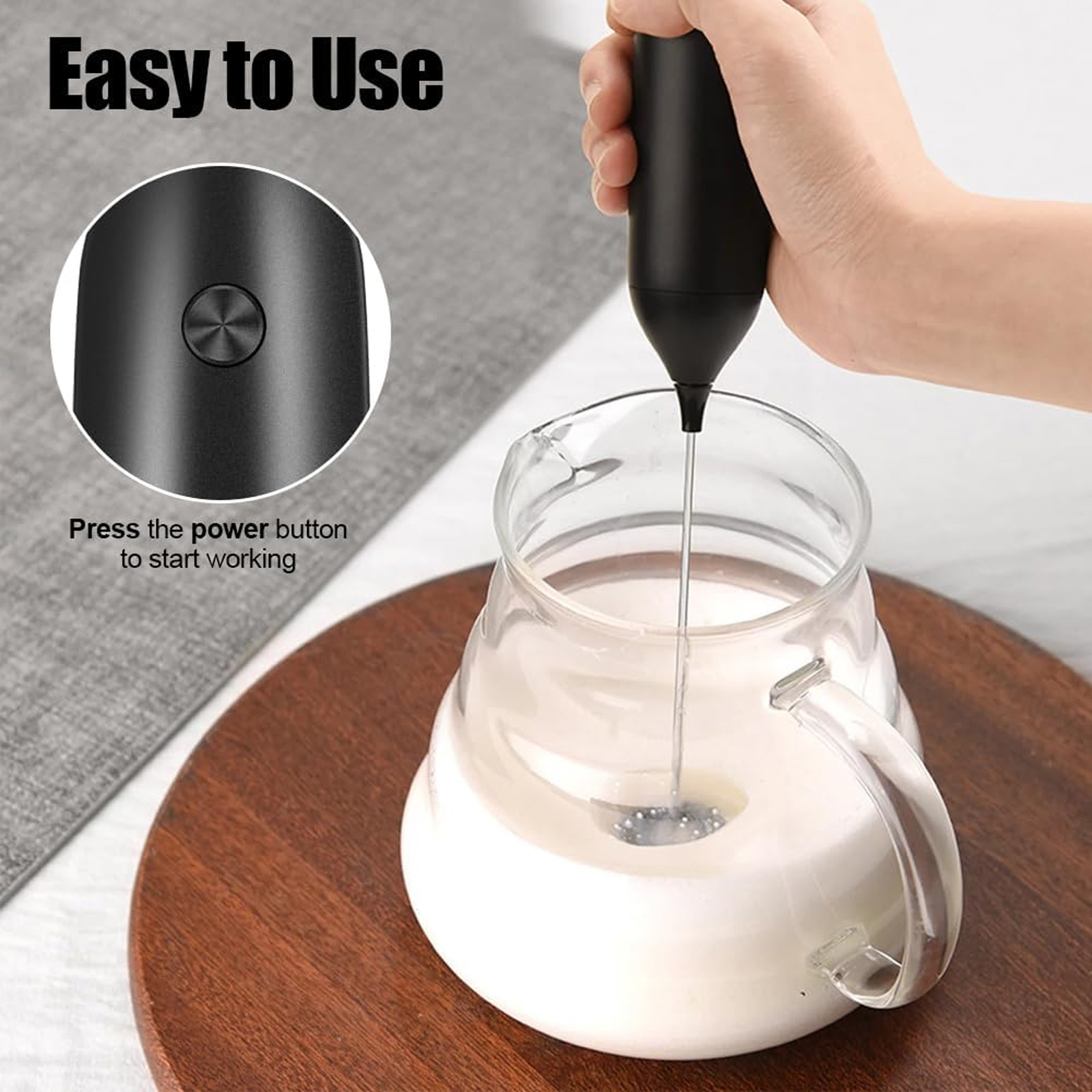 Handmixer schaumt Milch in Glasbehälter auf.