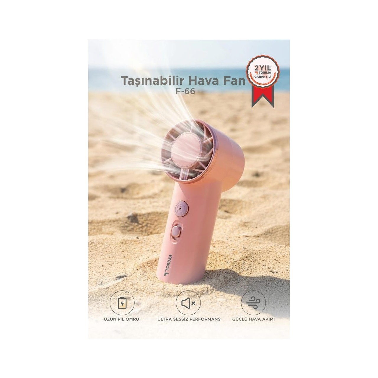 Pembe taşınabilir fan kumda duruyor, hava üflüyor. Metin: 2 yıl garanti.