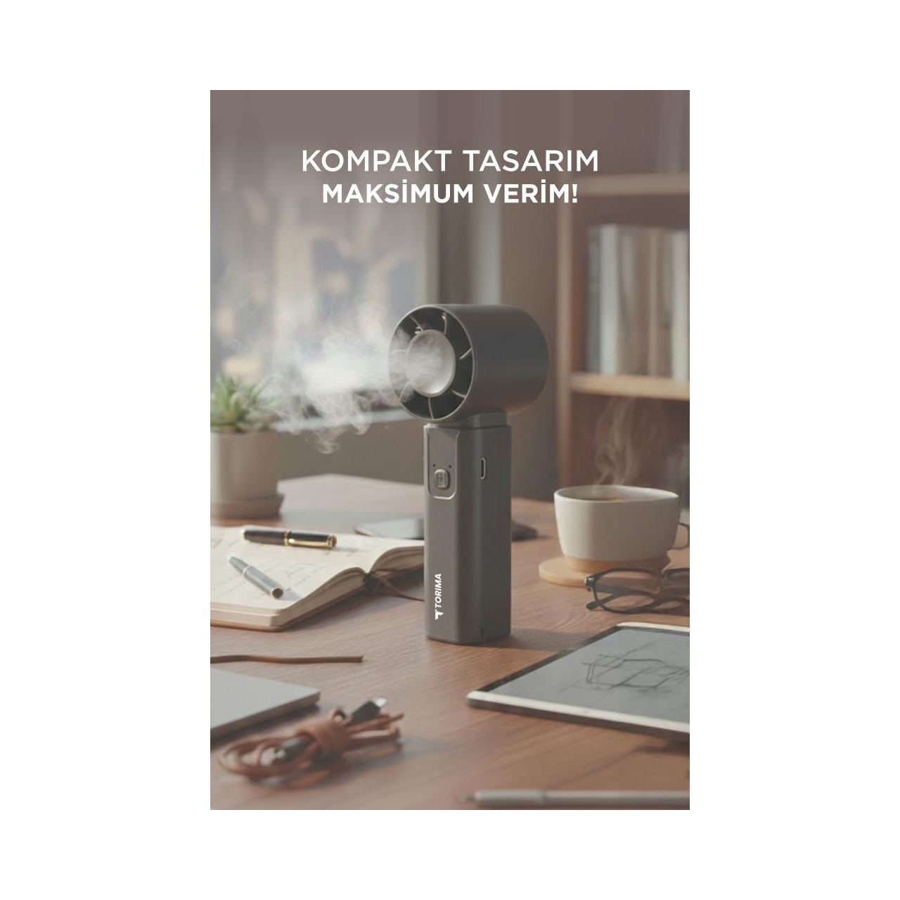 Koyu gri taşınabilir bir nemlendirici, ahşap bir masada defter, kalemler, tablet ve kahve fincanı ile buhar çıkarıyor.