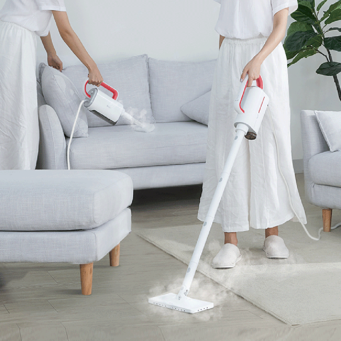 Zwei Personen in weißer Kleidung dampfreinigen ein Wohnzimmer mit weißen Möbeln.