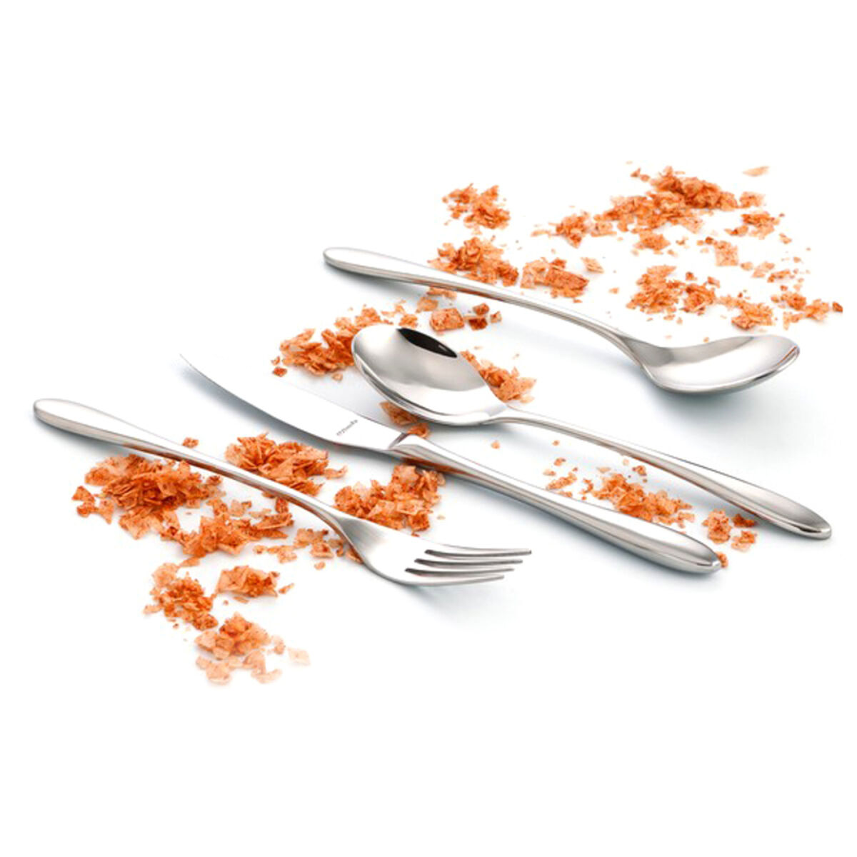 Besteckset mit Löffeln, Messer und Gabel, umgeben von Krümeln.