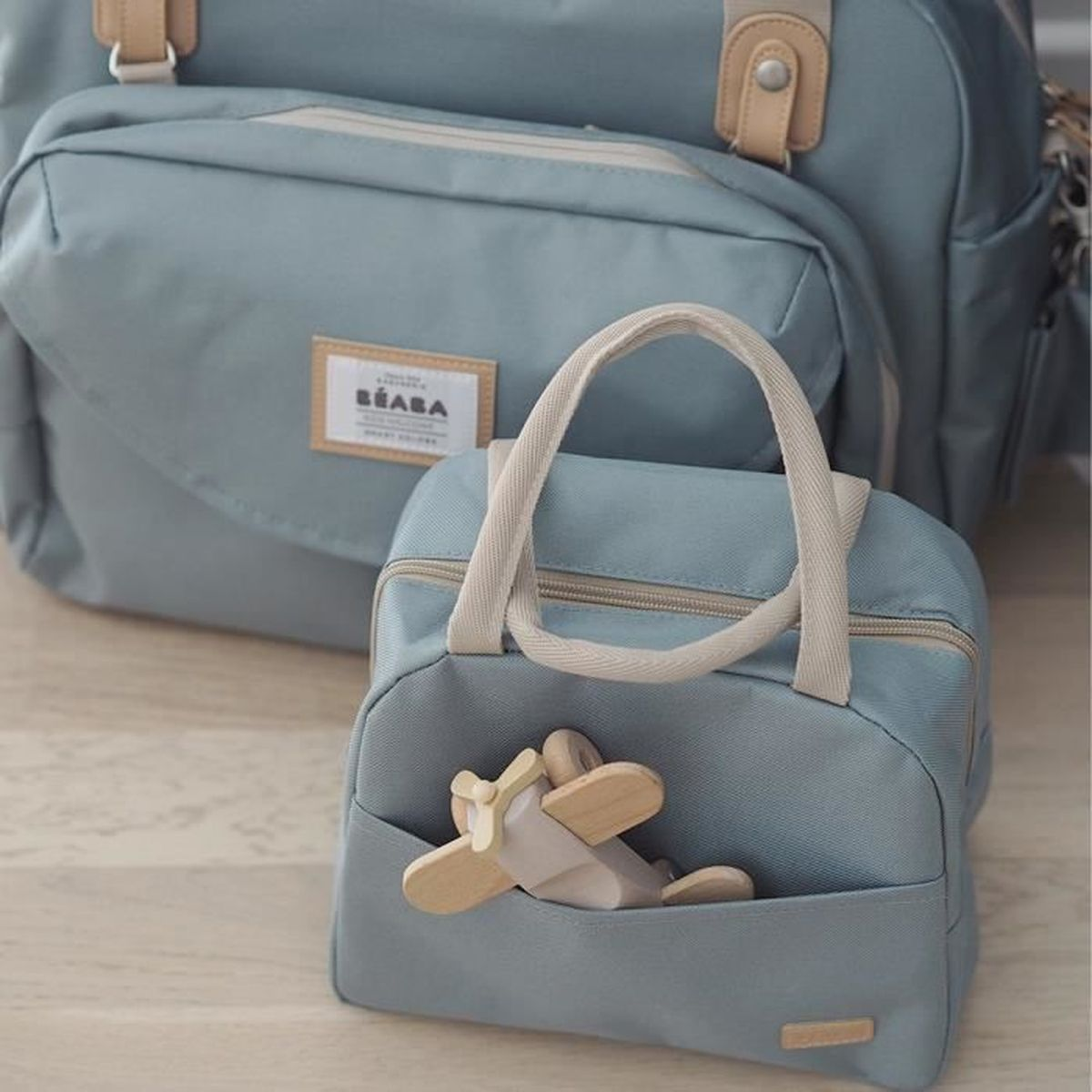 Zwei blaue Beaba-Taschen, eine mit Holzflugzeug im Fach.