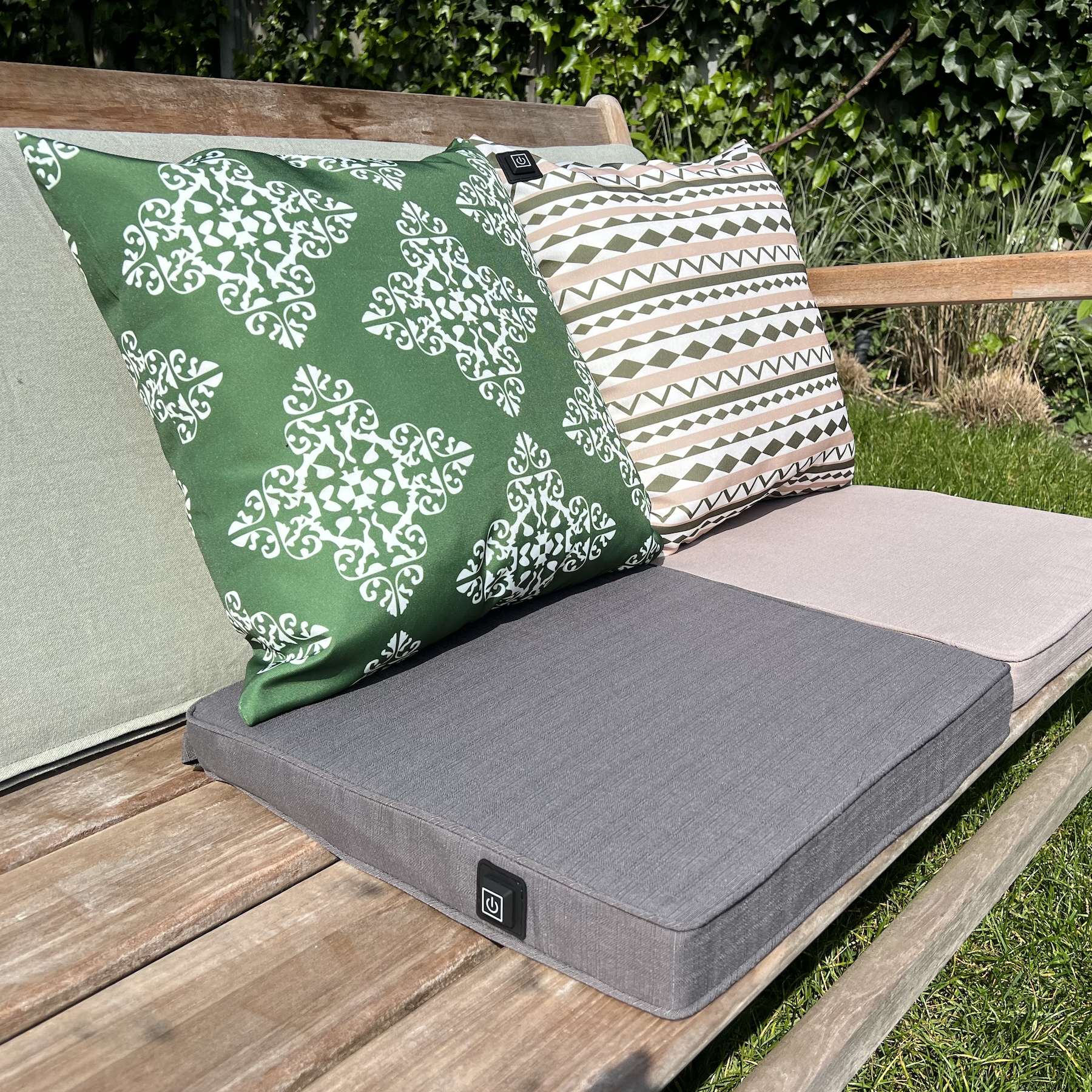 Eine Holzbank mit Kissen in Grün, Grau und Beige mit Mustern.