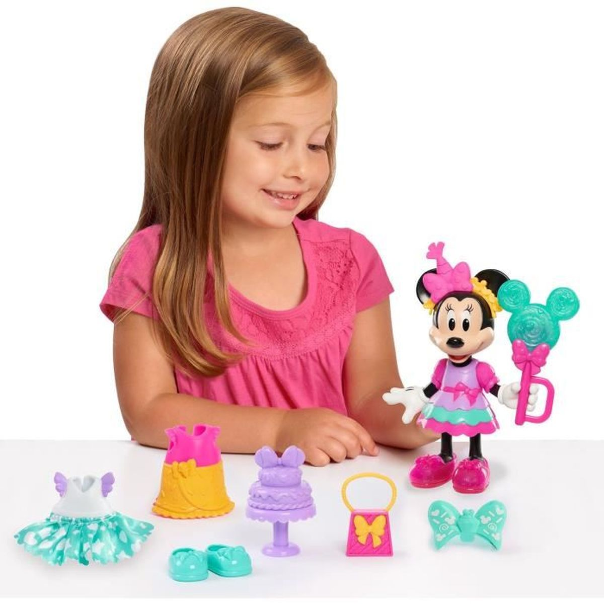 Ein Mädchen spielt mit einer Minnie-Maus-Figur und Kleiderzubehör.