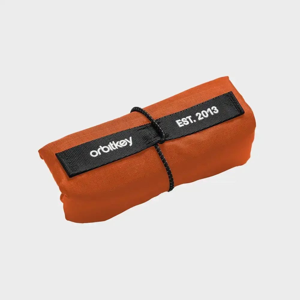 Pomarańczowy zwinięty przedmiot z czarnymi etykietami z napisem „orbitkey” i „EST. 2013”.