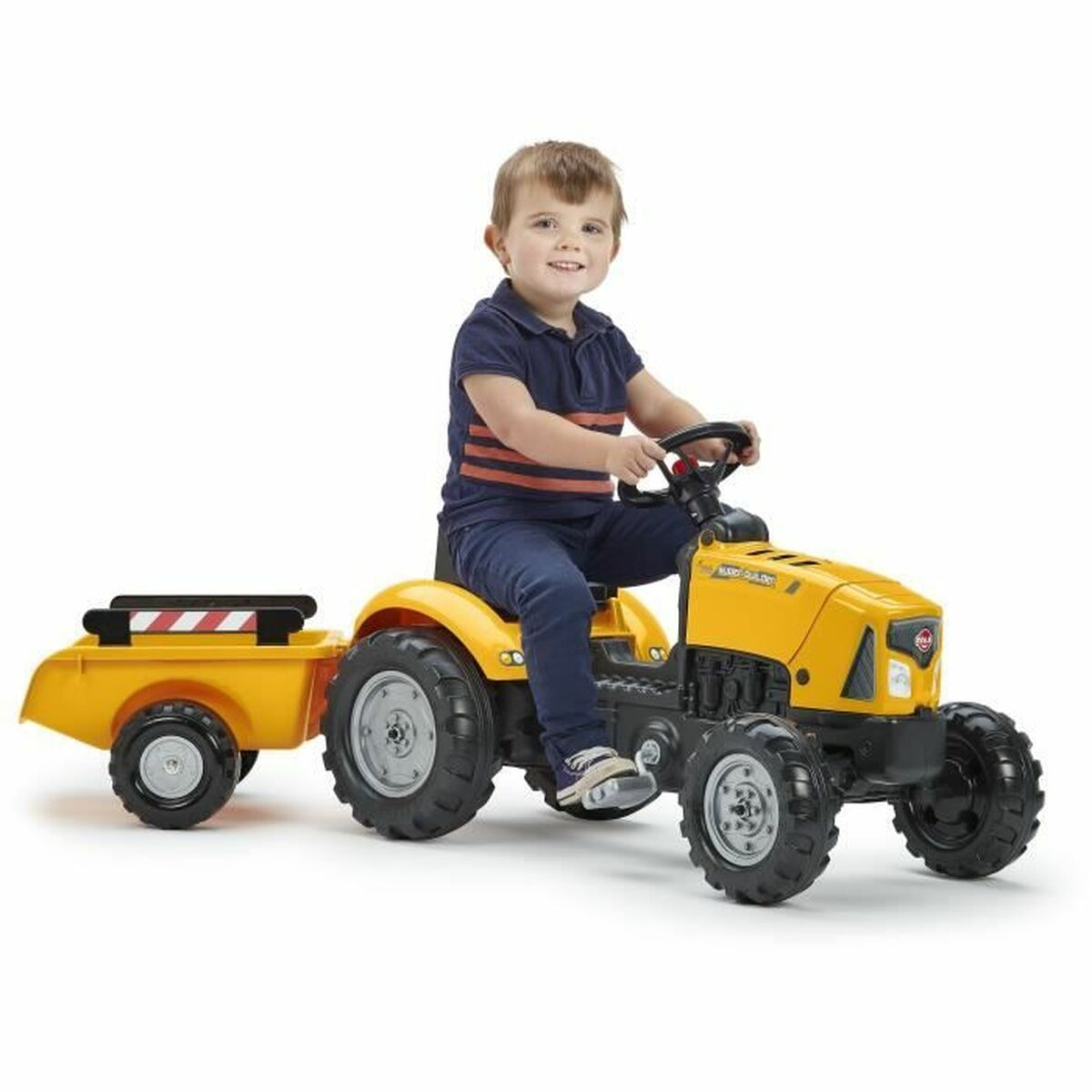 Ein Junge fährt einen gelben Spielzeugtraktor mit Anhänger.