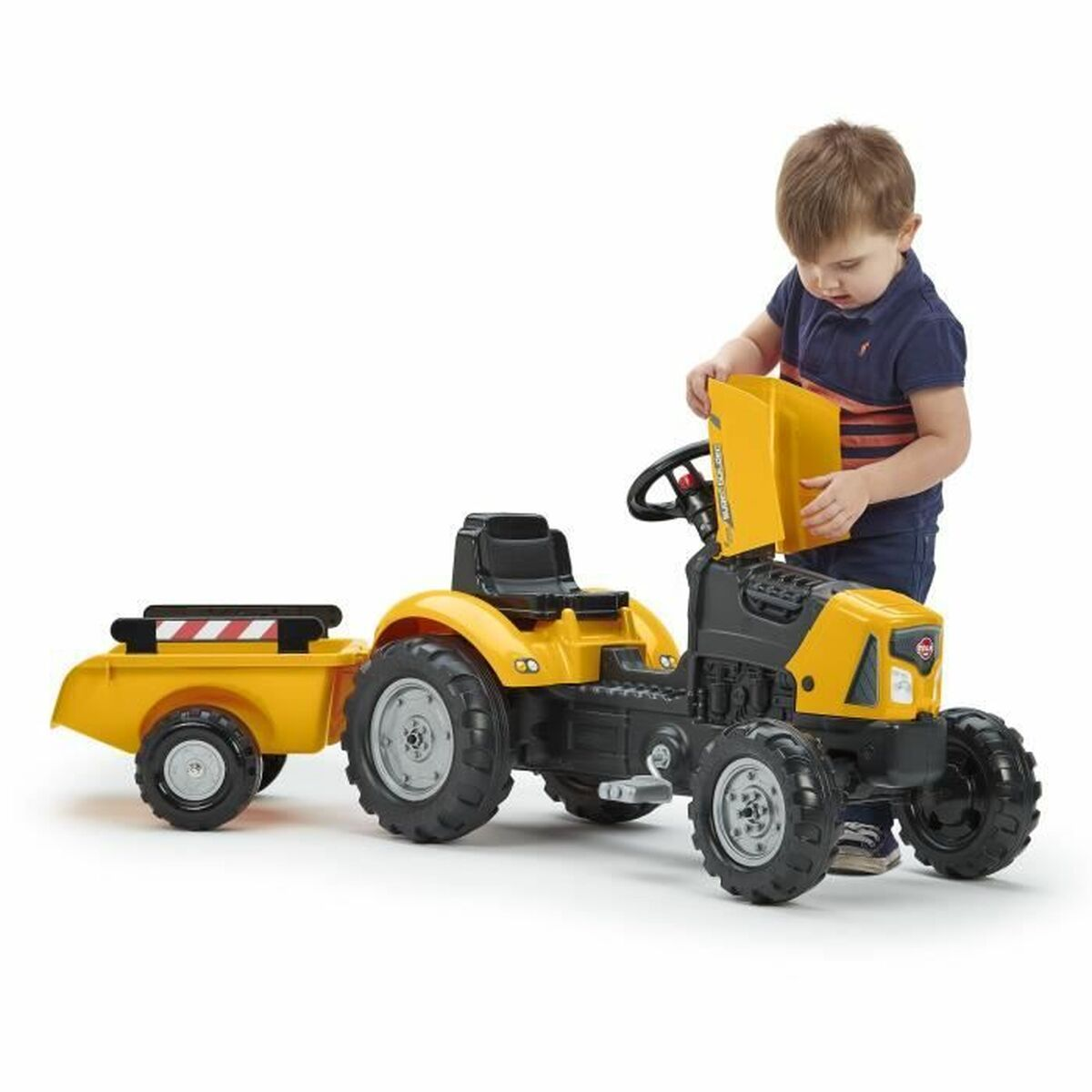 Ein Junge spielt mit einem gelben Spielzeugtraktor mit Anhänger.