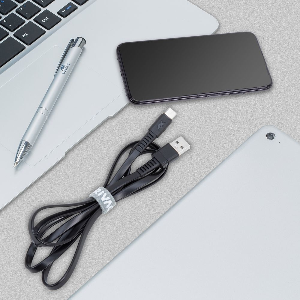 A laptop, smartphone, charging cable, and pen on a gray surface.