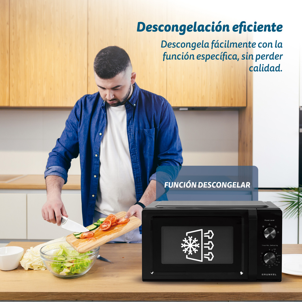 Uomo prepara verdure accanto a microonde nero con funzione scongelamento.