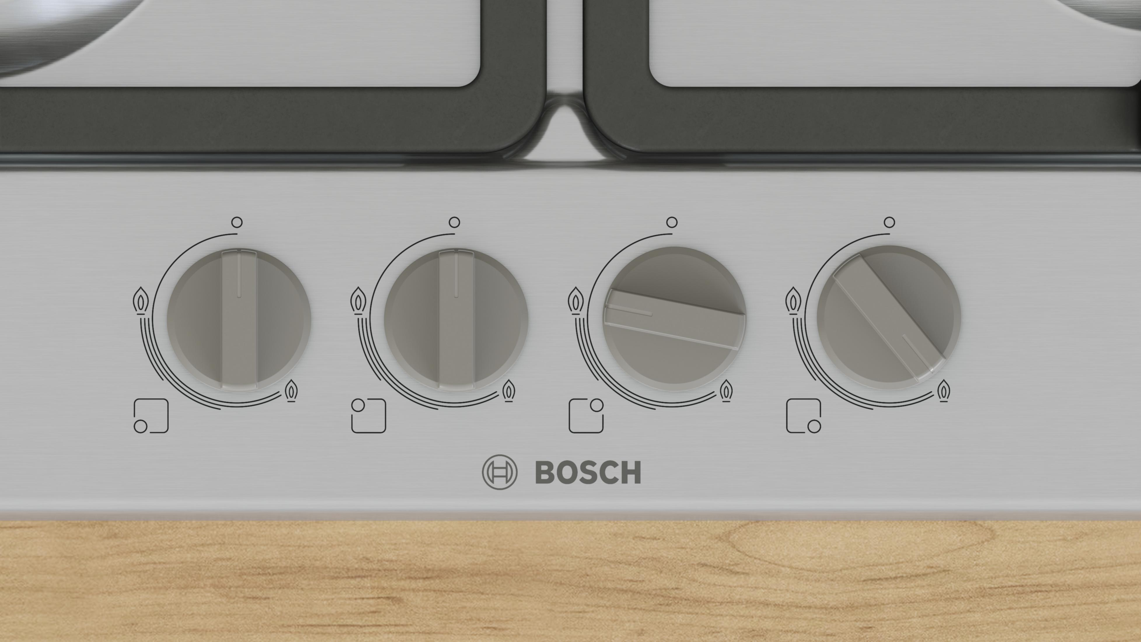 Close-up of four gray control knobs on a silver stovetop with a Bosch logo.