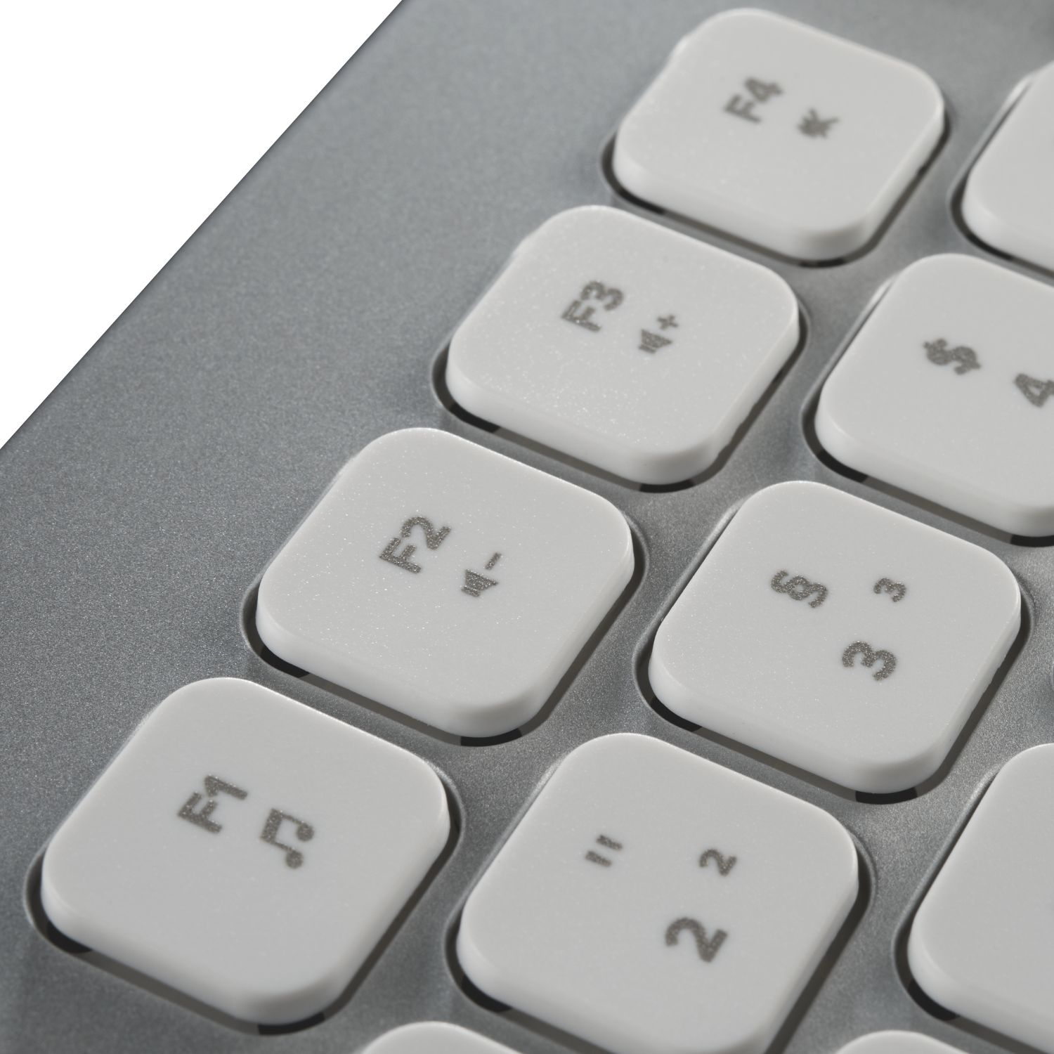 Eine Nahaufnahme von weißen Tastenkappen auf einer silbernen Tastatur. F1, F2, F3, F4 sind sichtbar.