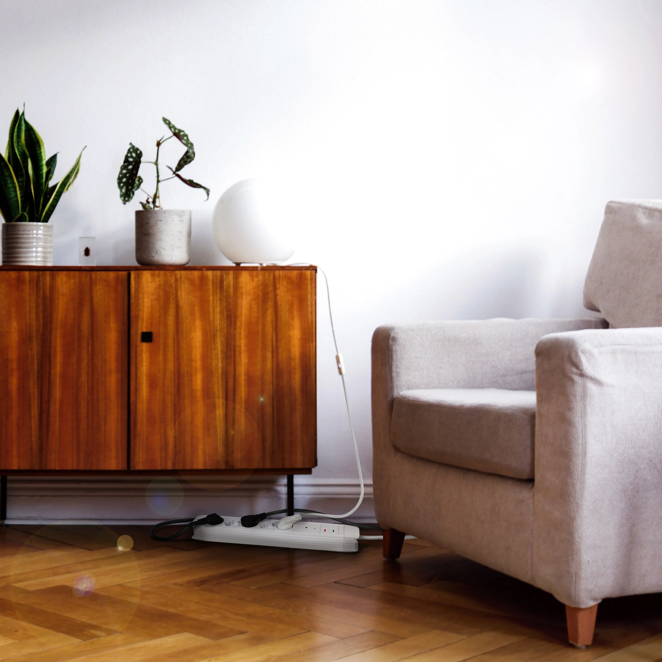 An armchair sits beside a wooden cabinet with plants and a lamp.