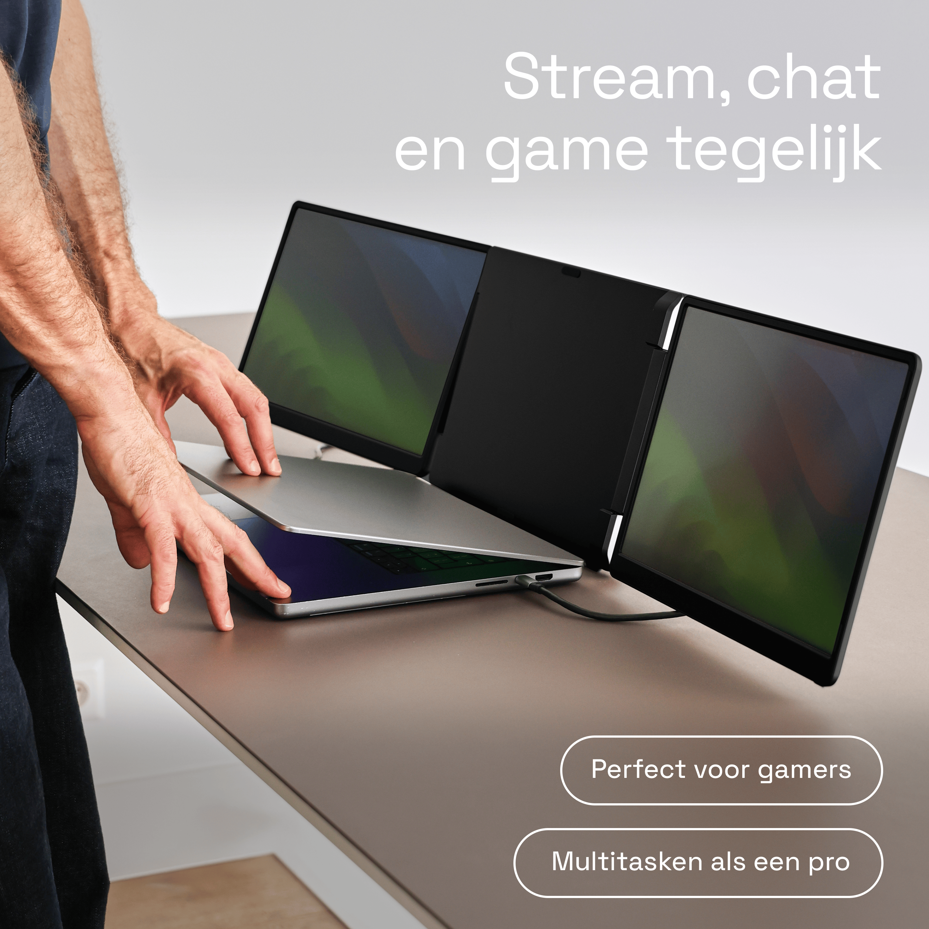 Un ordinateur portable ouvert entre deux moniteurs externes. Des mains touchent le clavier.