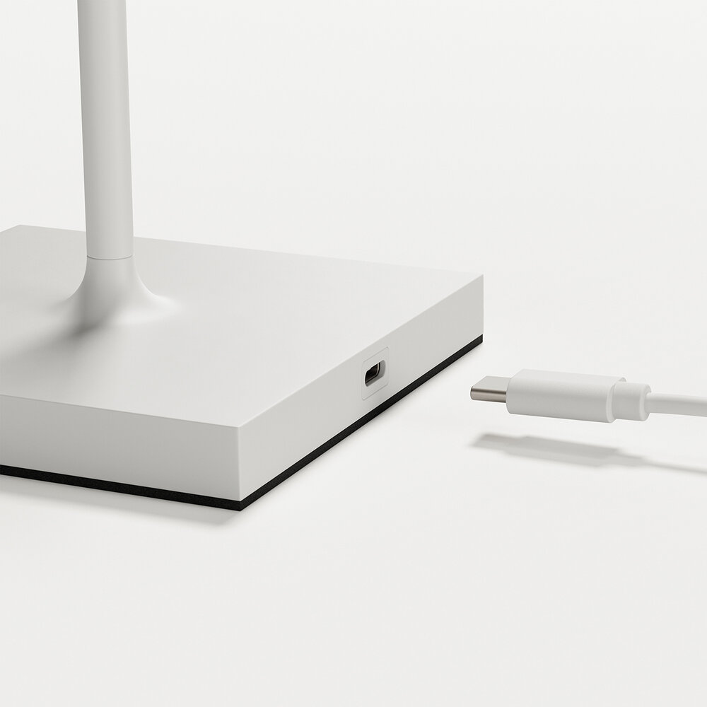 Ein weißes Kabel mit USB-C-Stecker liegt neben einer weißen Basis mit einem Anschluss.
