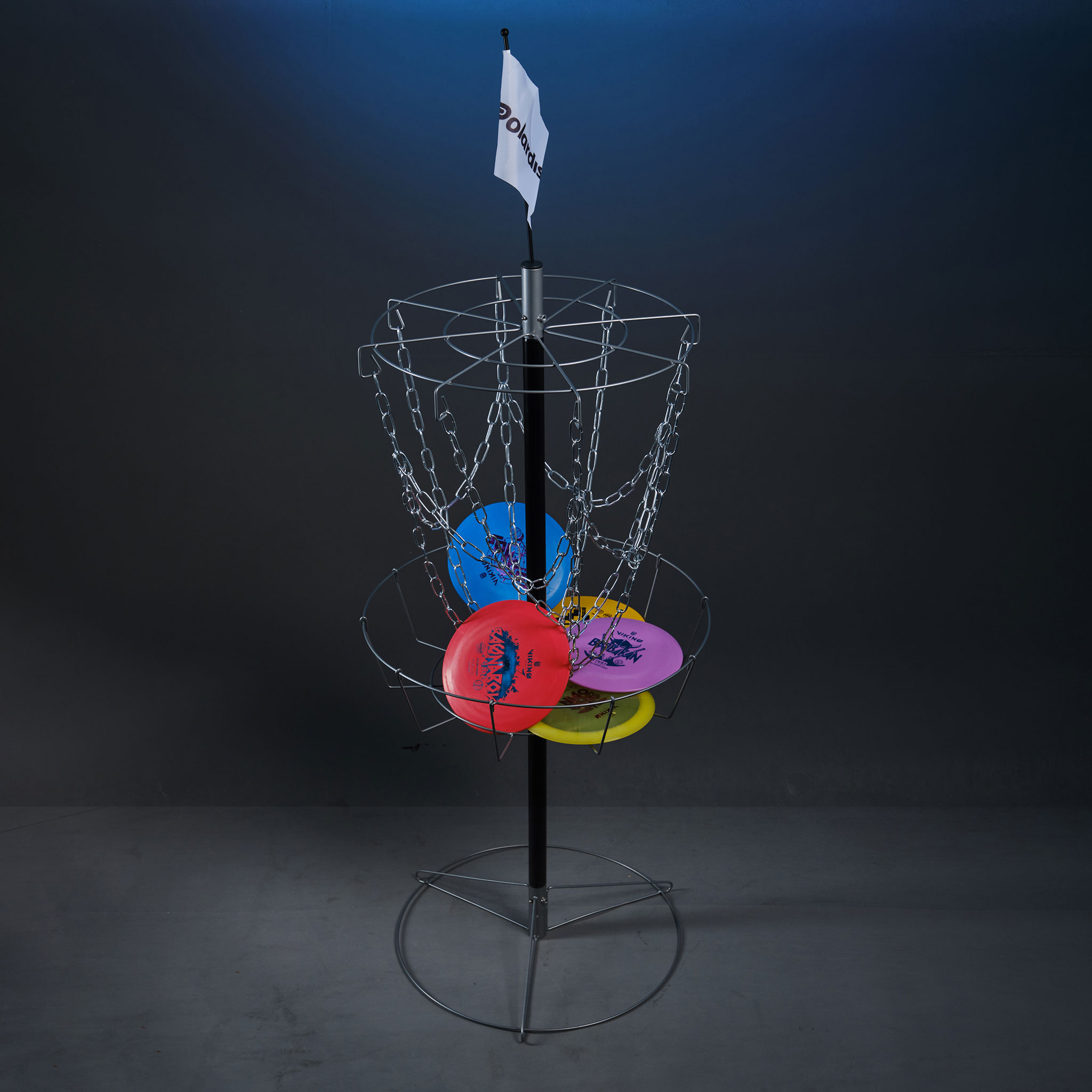 Discgolfkorb mit vier bunten Scheiben und einer weißen Fahne.