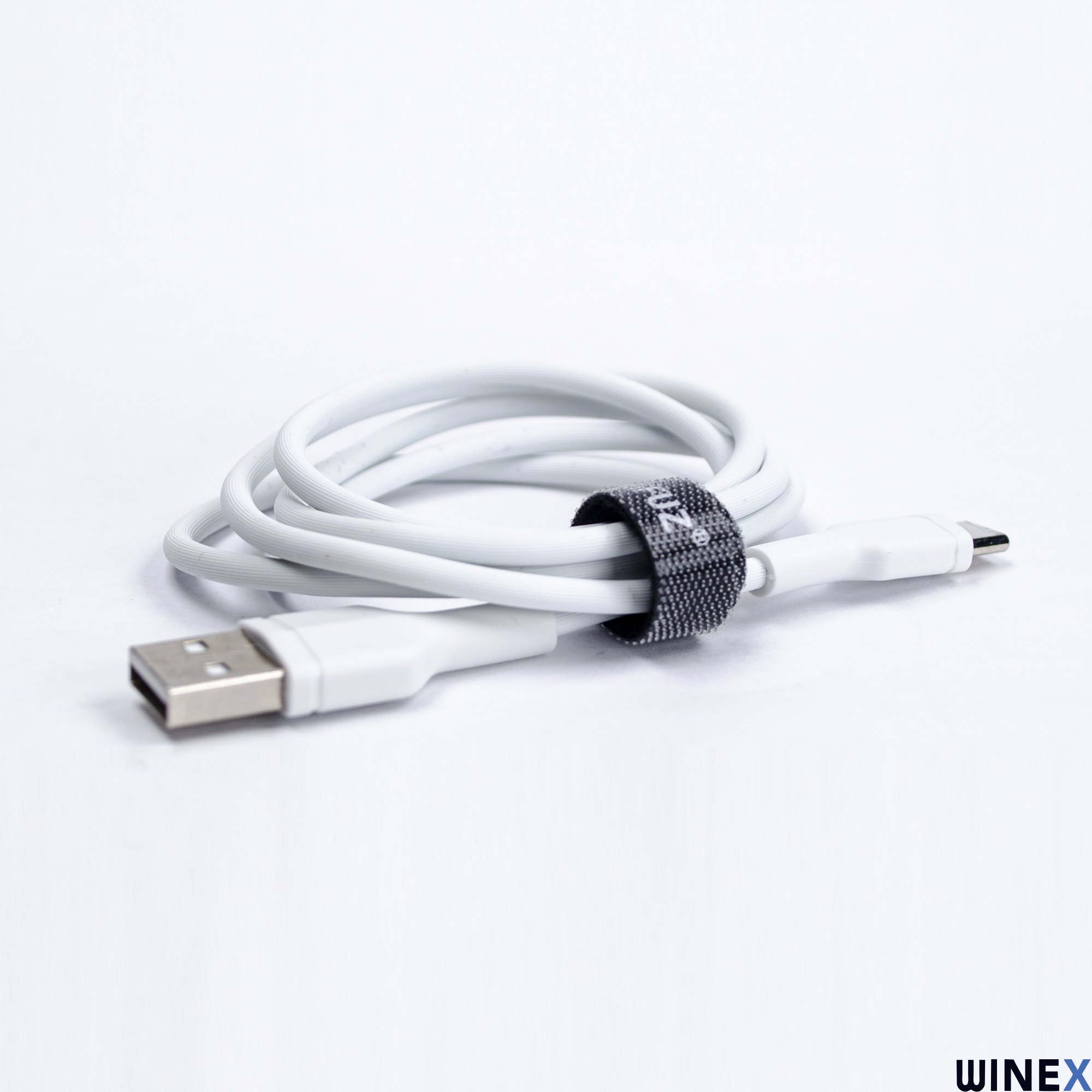 Beyaz arka plan üzerinde siyah kablo bağına sahip beyaz USB kablosu.