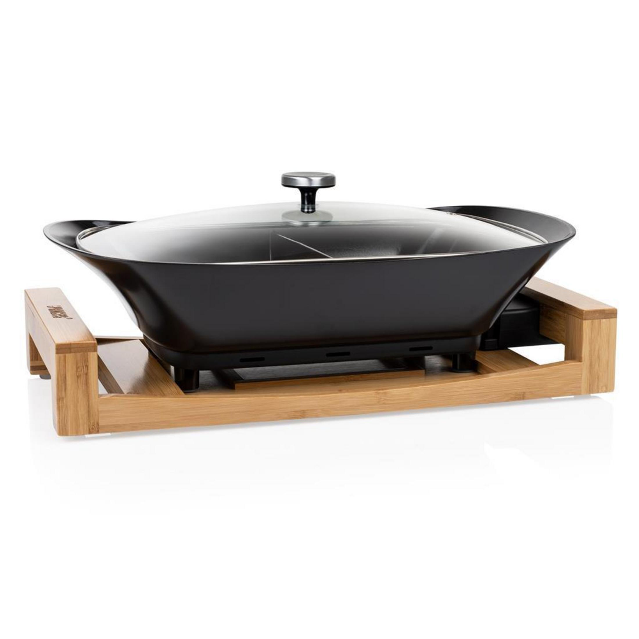 Una sartén wok negra con tapa de cristal sobre un soporte de madera.
