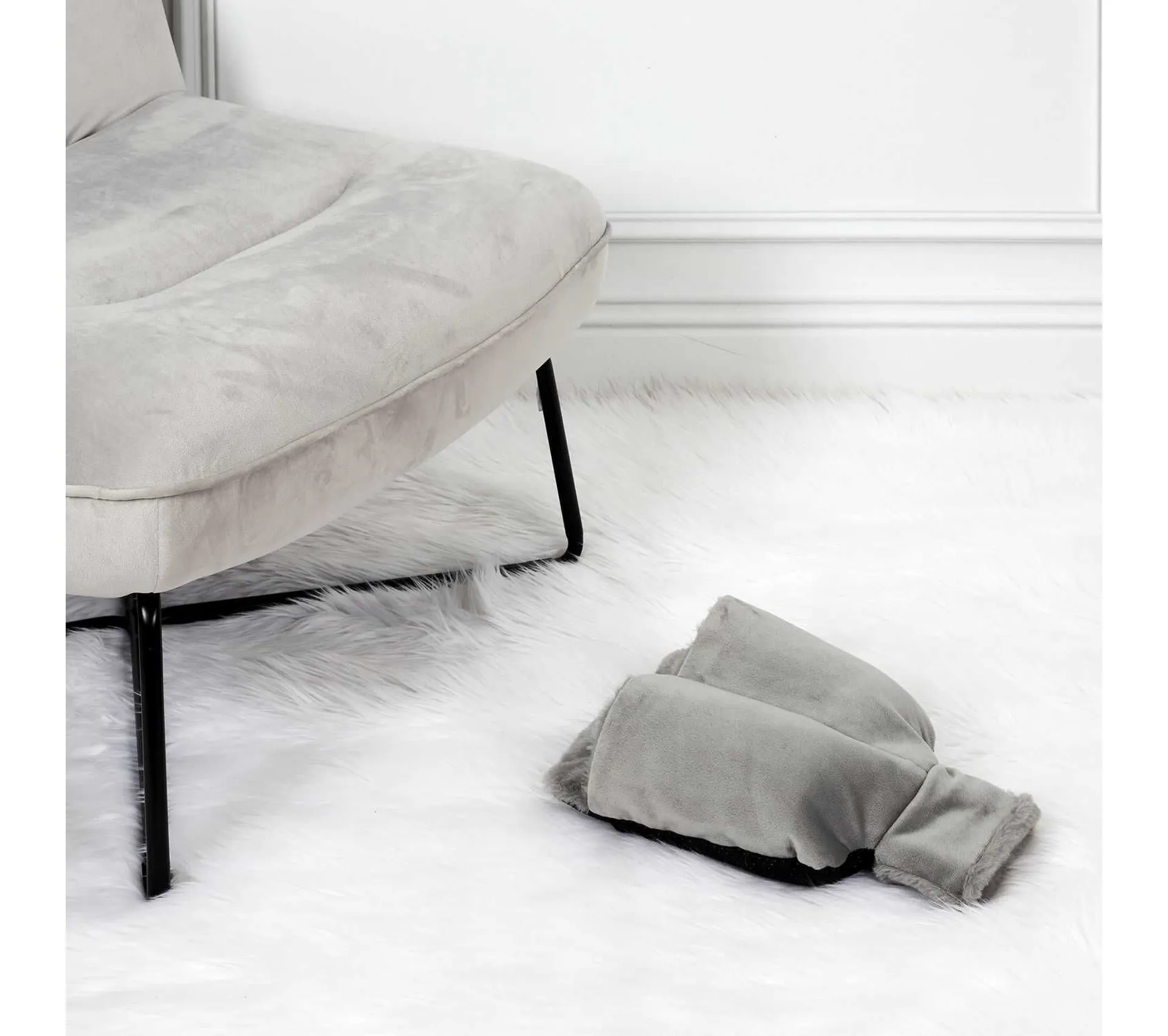 Poltrona grigia su tappeto bianco a pelo lungo con scaldapiedi grigio.