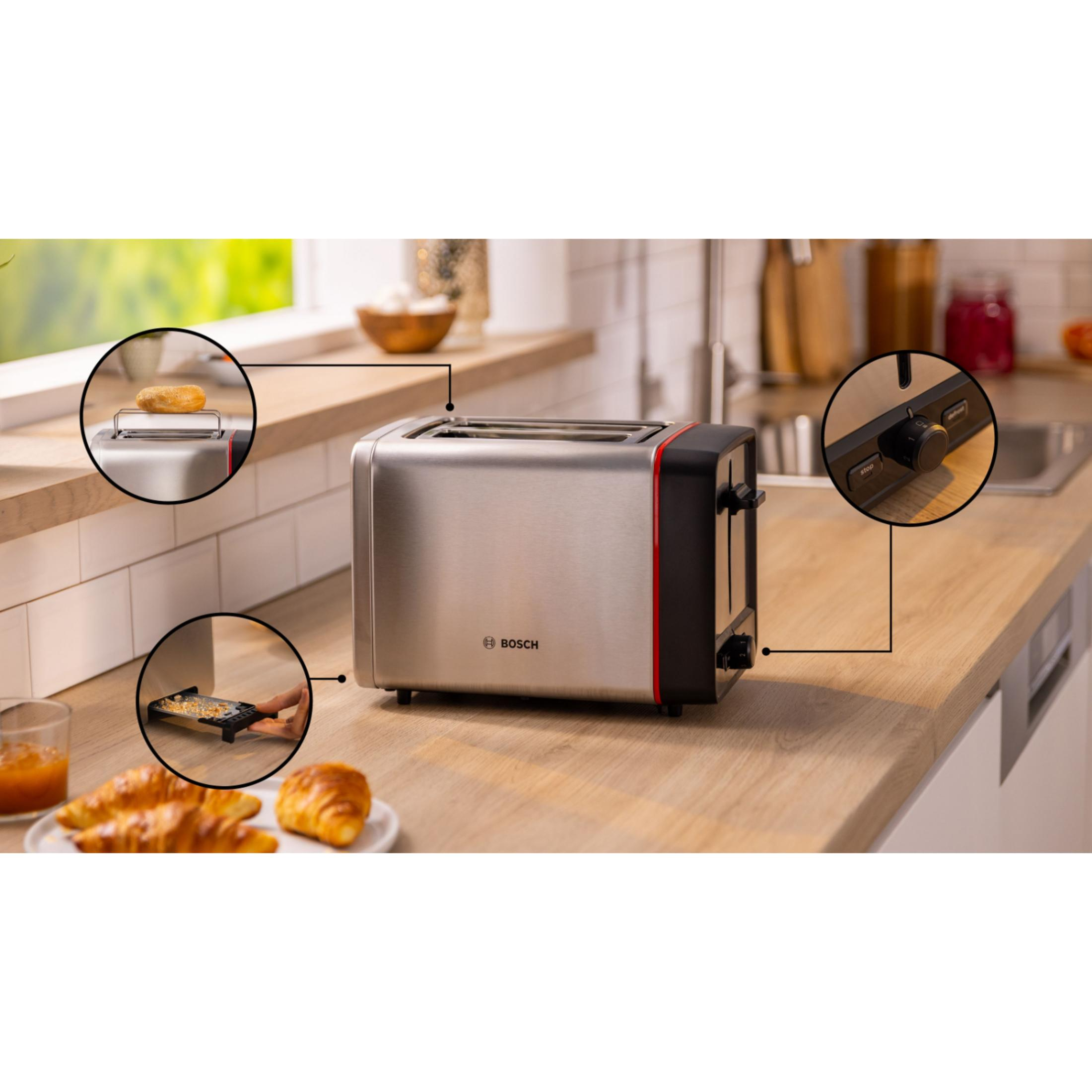 A silver Bosch toaster with red accents sits on a wooden counter. Croissants and jam are nearby.
