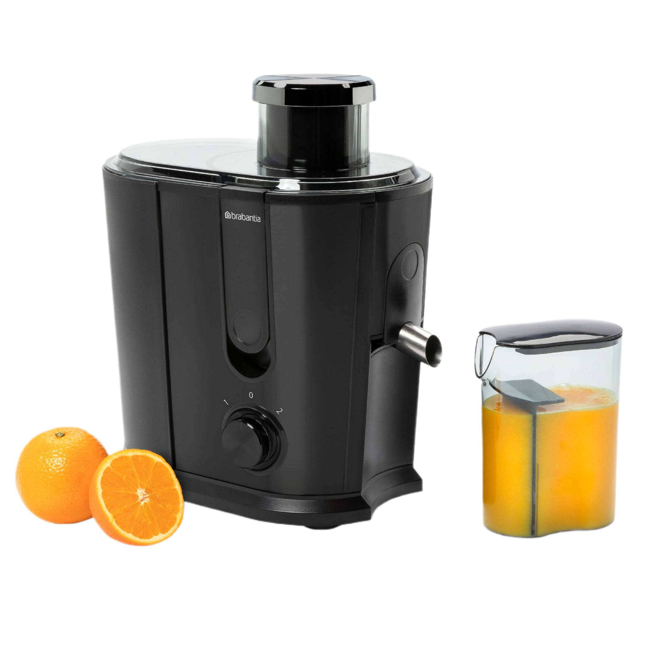 Schwarzer Entsafter mit zwei Orangen und einem Glas Orangensaft.