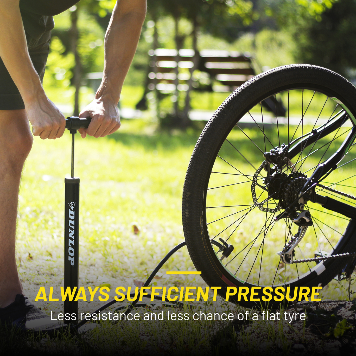 Man pumps bicycle tire with black pump outdoors on grass.