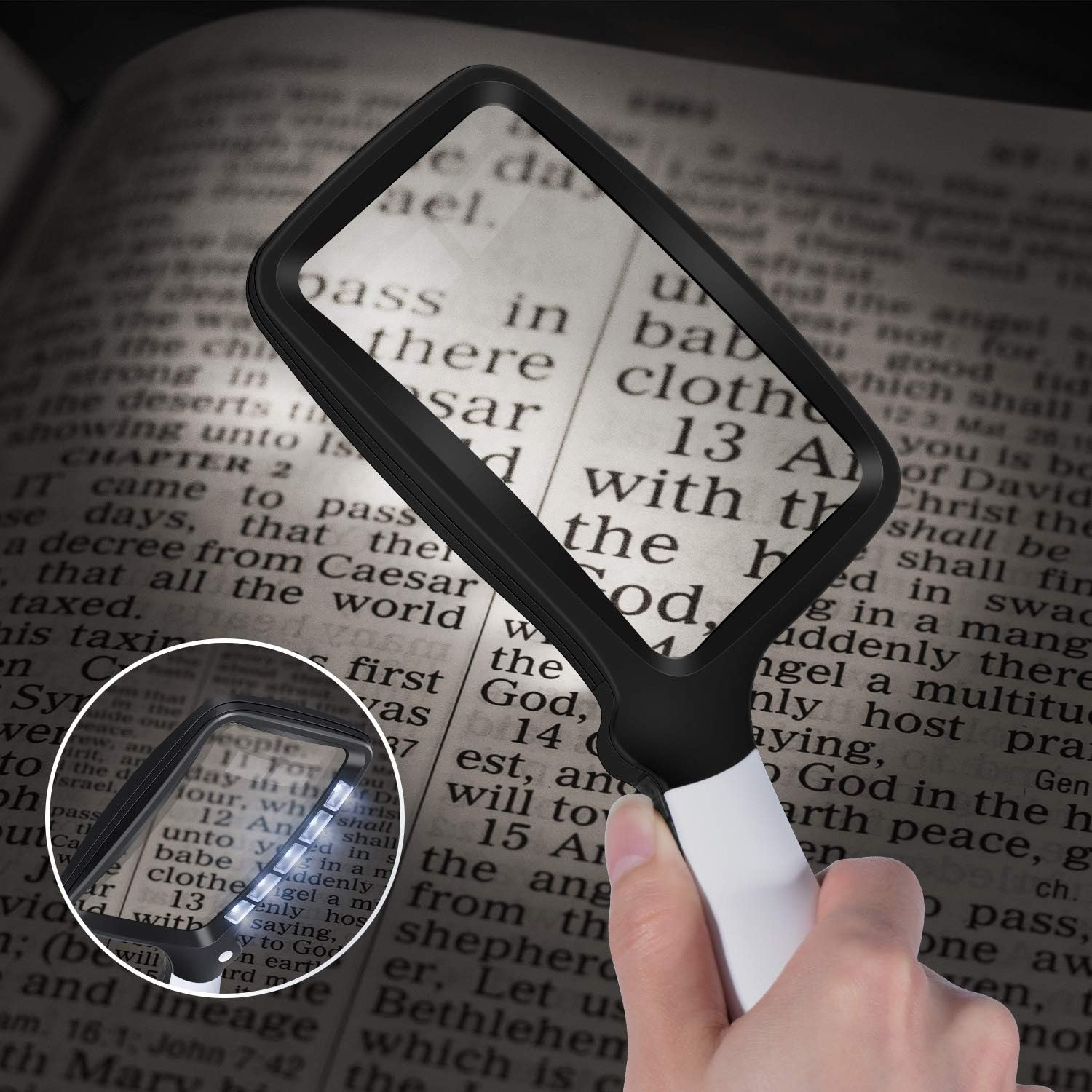 Eine Hand hält eine Lupe über ein offenes Buch und beleuchtet den Text mit LEDs.
