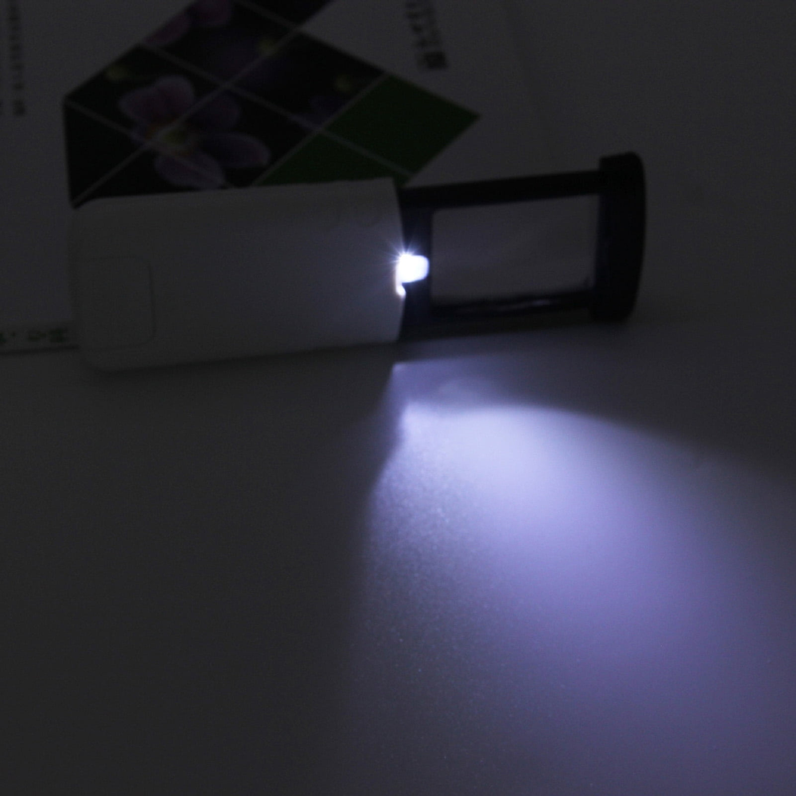 Eine Lupe mit Licht leuchtet auf eine dunkle Oberfläche.