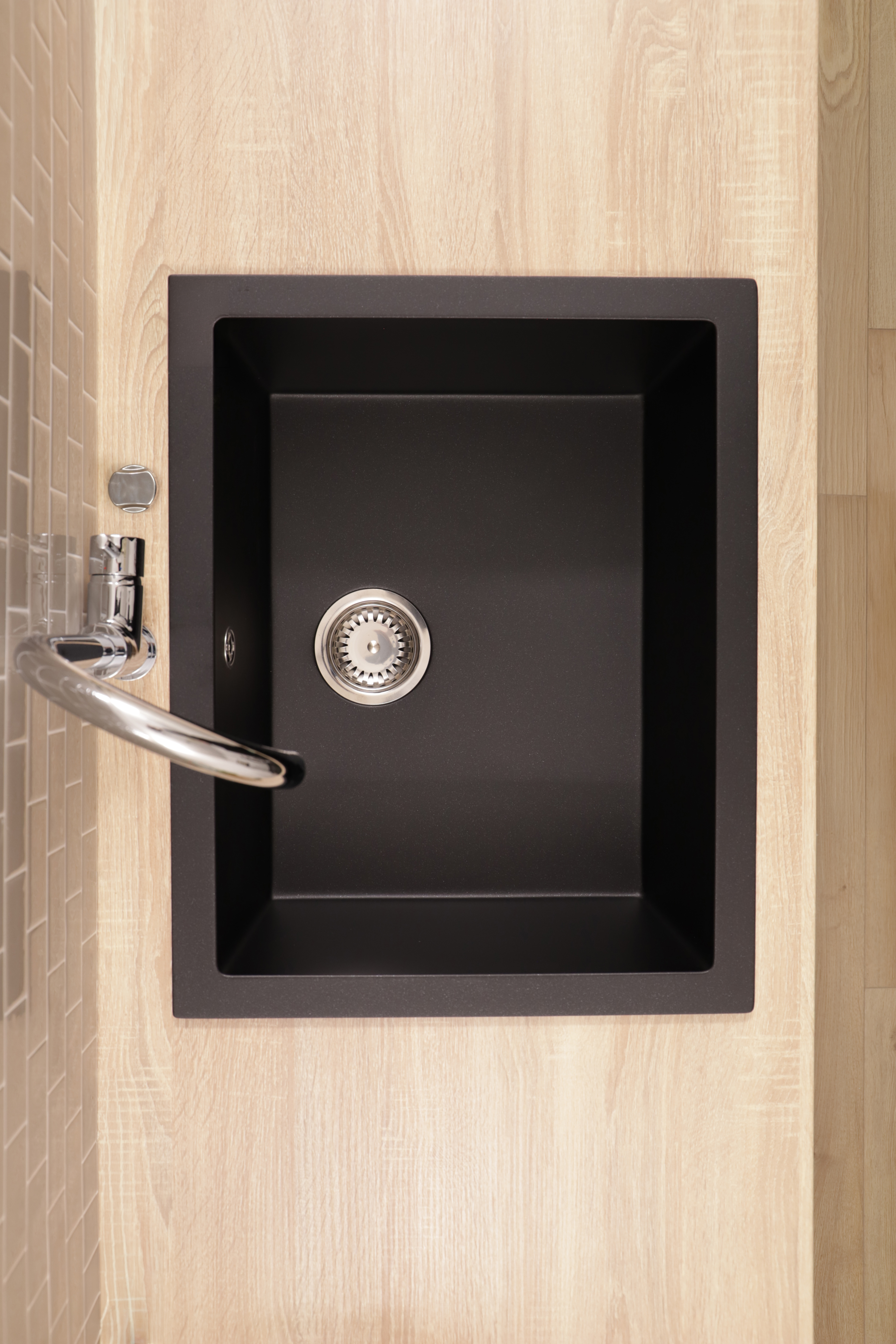 Ein schwarzes Spülbecken mit Chromarmatur auf einer Holzarbeitsplatte.